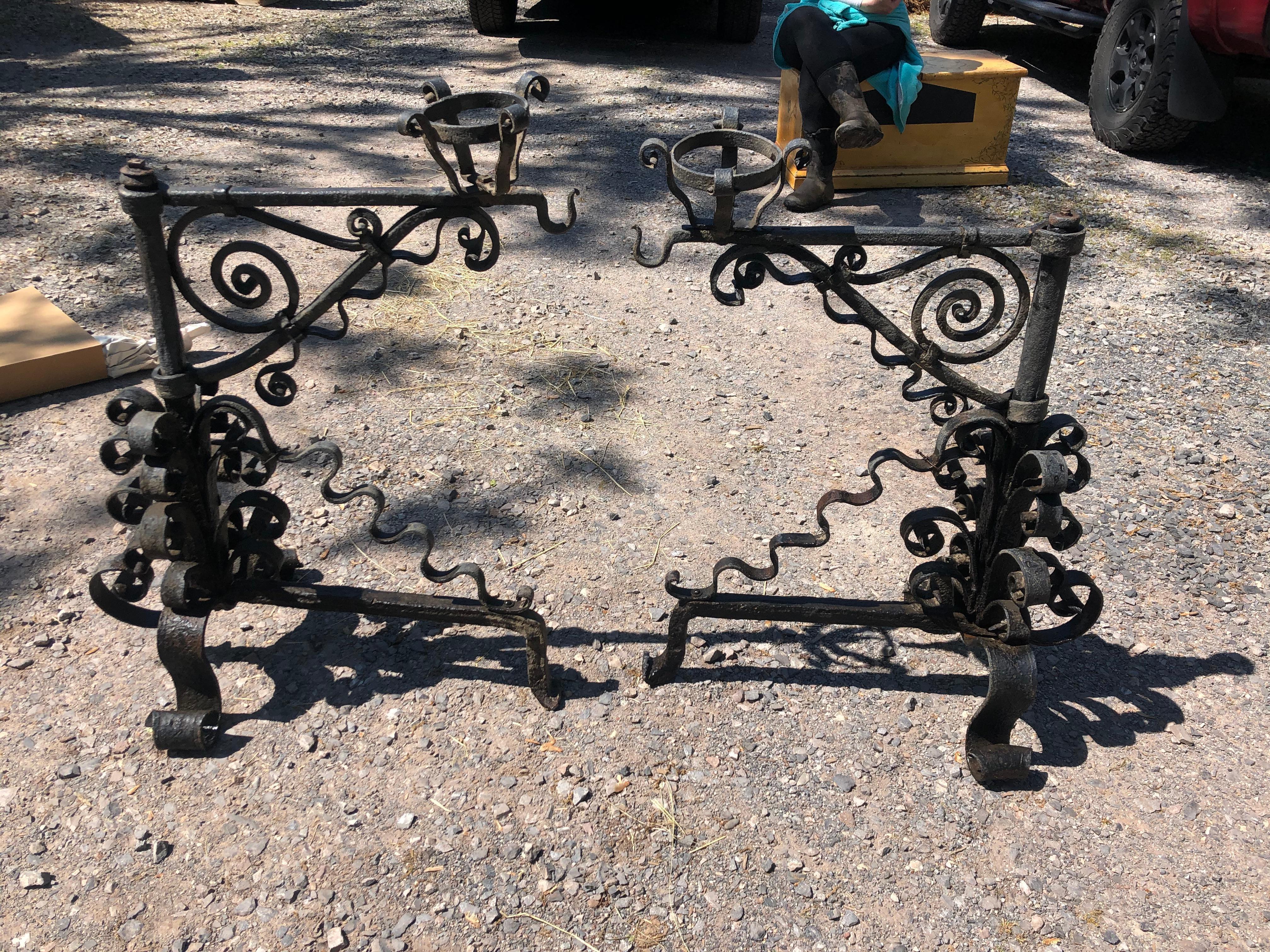Truly belong in a castle, a pair of palatial, large black iron andirons adorned with curlicues and hooks for hanging cookware. 
 