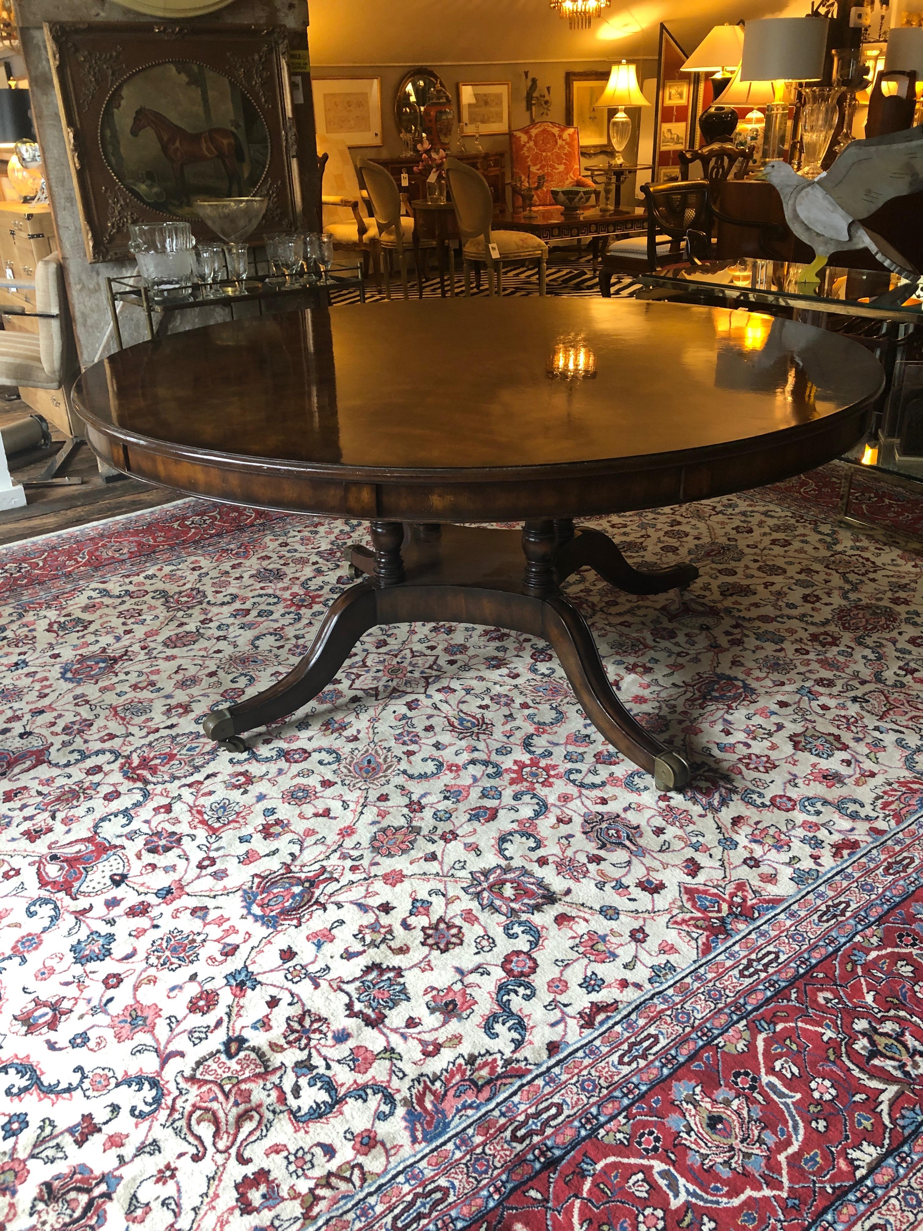Incredibly made Regency crotch mahogany turn of the century dining table. Having sunburst central inlay and 5 leaves that attach around the periphery to make a very grand large round table. Without the leaves table is 63.25