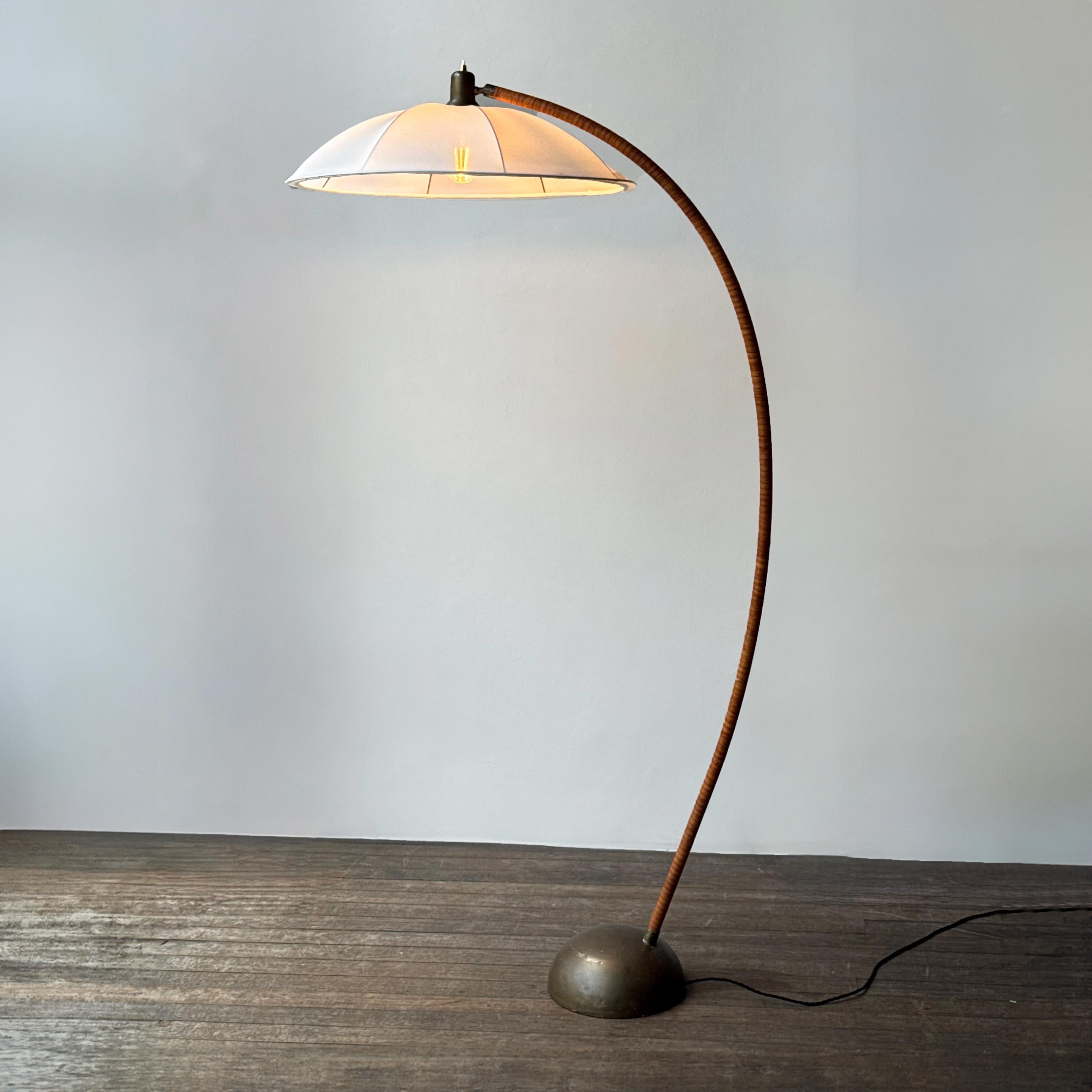 Description: 
A leather bound arched floor lamp with weighted brass base and its original, custom sun-ray lampshade, recently restored with an ivory stretch silk. Likely made in the Nordics during the late 1950s- early 1960s, the stem of this