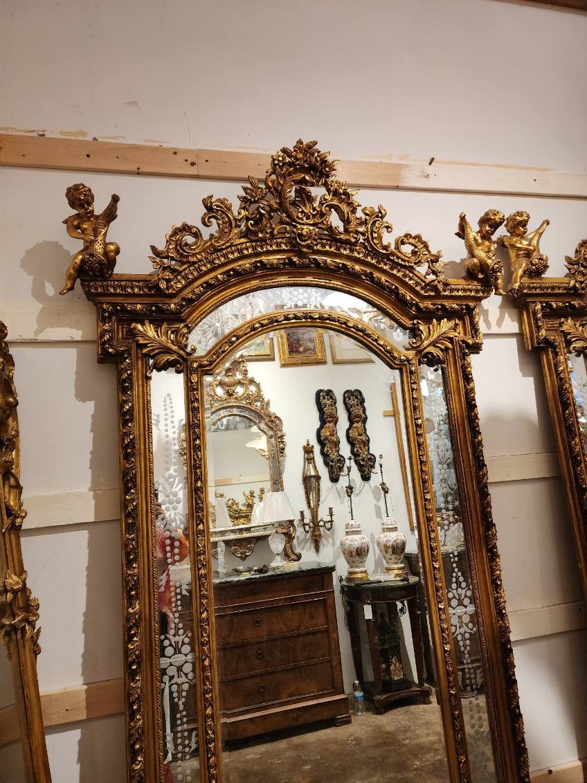 Paire de miroirs dorés de style Louis XV, chacun avec des putti/chérubins ailés. 