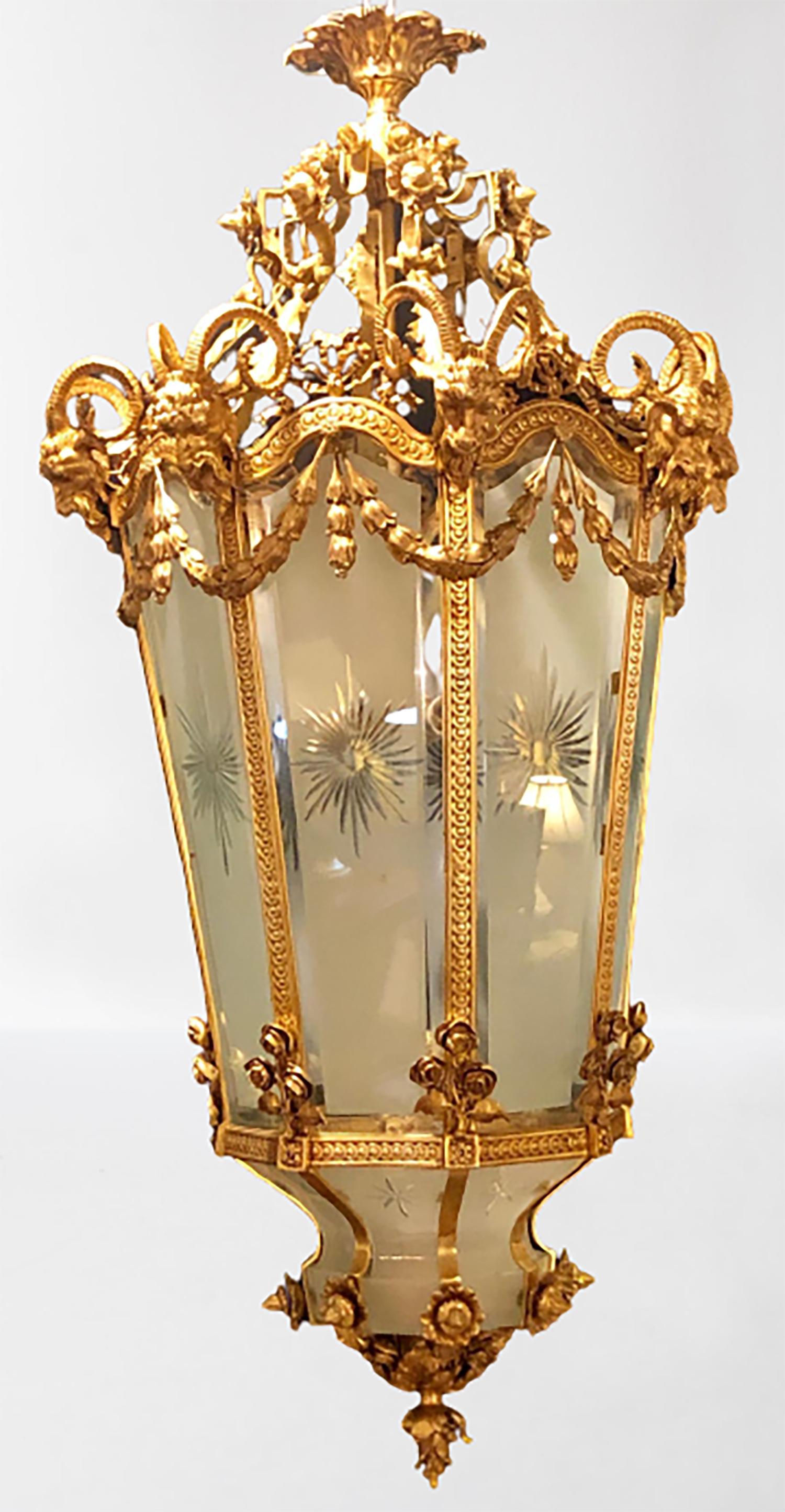 A Louis XVI style monumental Dore bronze rams head etched glass lantern. This spectacular one of a kind lantern is simply too stunning to behold. The frosted and etched star burst curved panels of glass framed in a heavy thick gilt gold bronze of