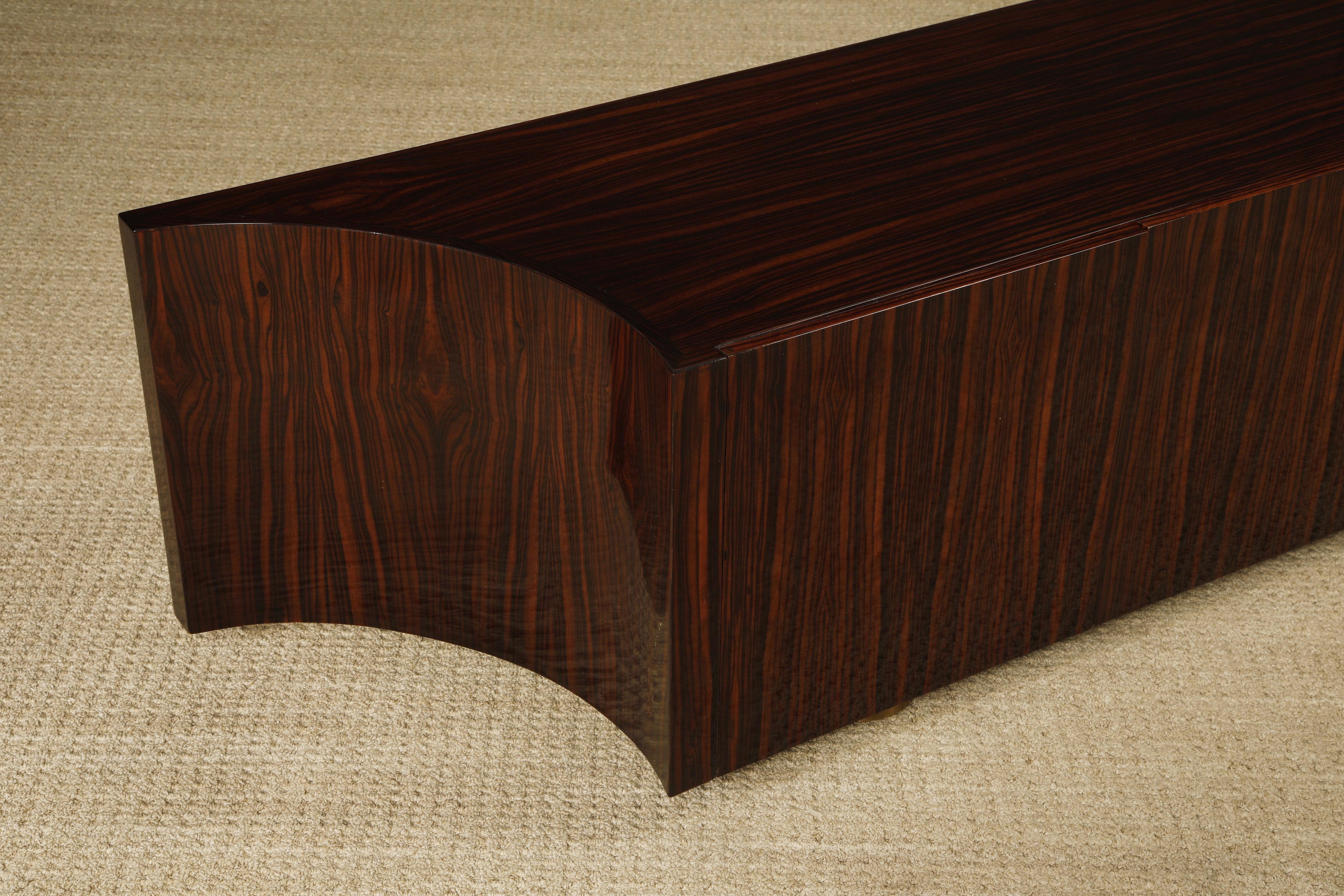 Questa credenza monumentale si estende per oltre 3 metri con un legno esotico di Ebano Macassar, rifinito su entrambi i lati, con pesanti accenti in ottone e piedini a disco regolabili in altezza. Un lato è smerlato e può essere utilizzato per