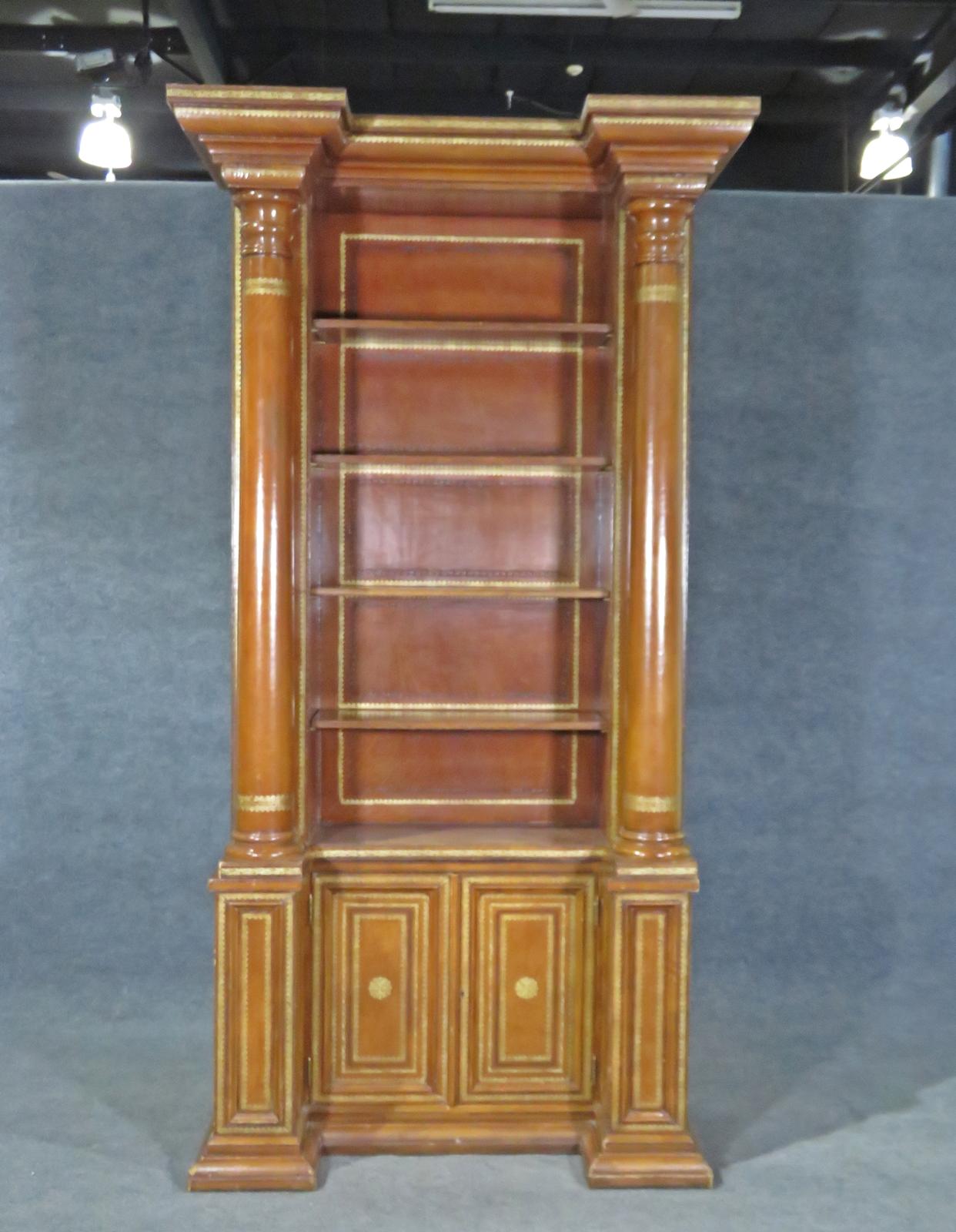 This is a fantastic and very tall leather-wrapped gold-tooled embossed bookcase with 4 shelves and it is in two pieces. The cabinet is a masterpiece and has a very stately appearance. There are 4 shelves. Measures: 96 1/2