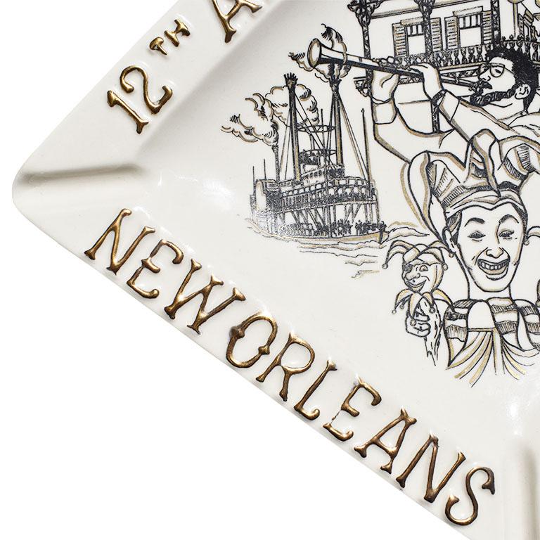 A tall diamond-shaped ceramic ashtray with a Mardi Gras theme motif. This ashtray would be fabulous displayed on a coffee table or nightstand. It is glazed in cream, and features raised text around the edge of the dish in gold which says, 