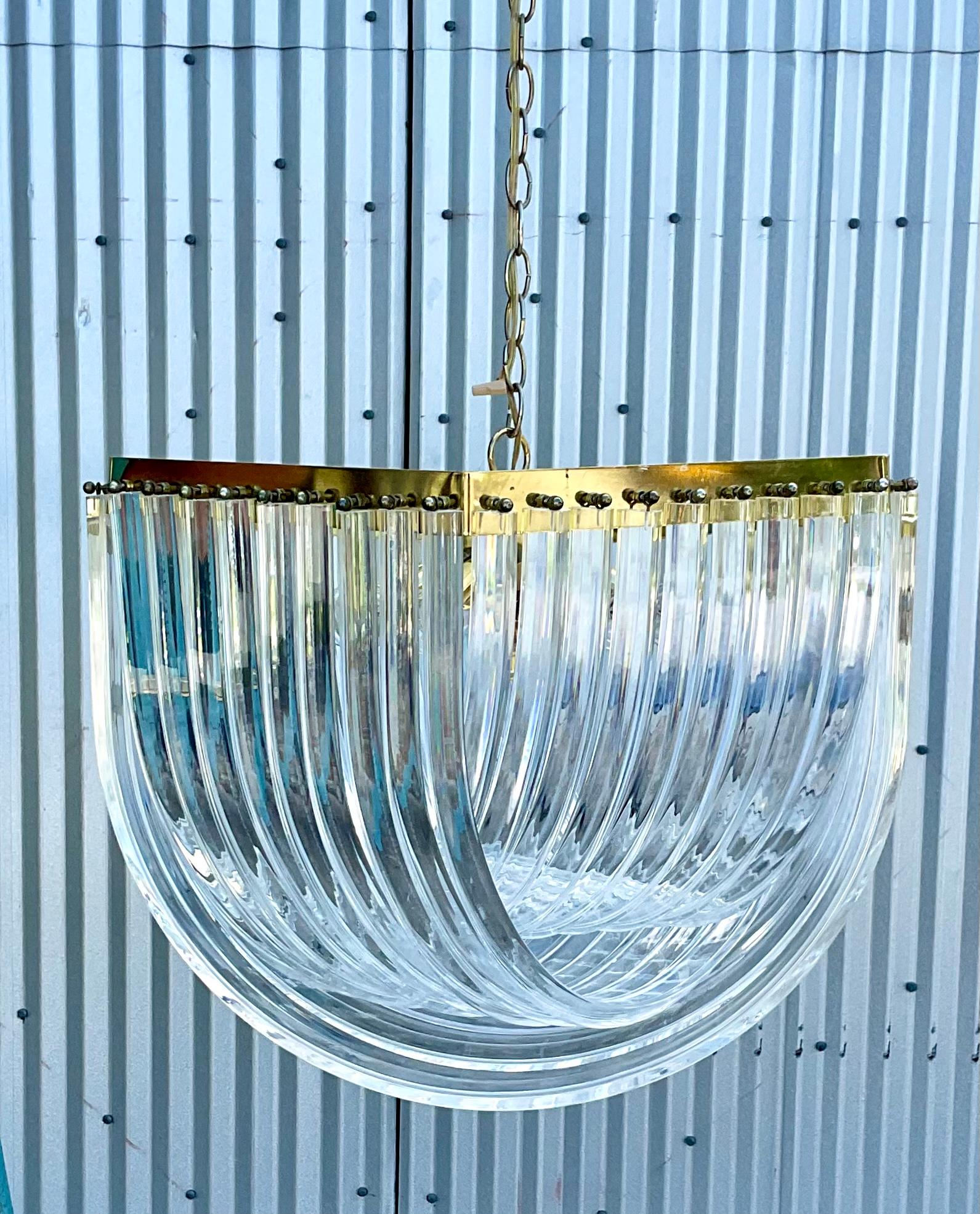 Spectacular vintage MCM brass and lucite ribbon chandelier. Much larger than anything I have seen on the market. Beautiful clear ribbons of lucite hand from a brass frame. A glamorous addition to any decor. Acquired from a Palm Beach estate.