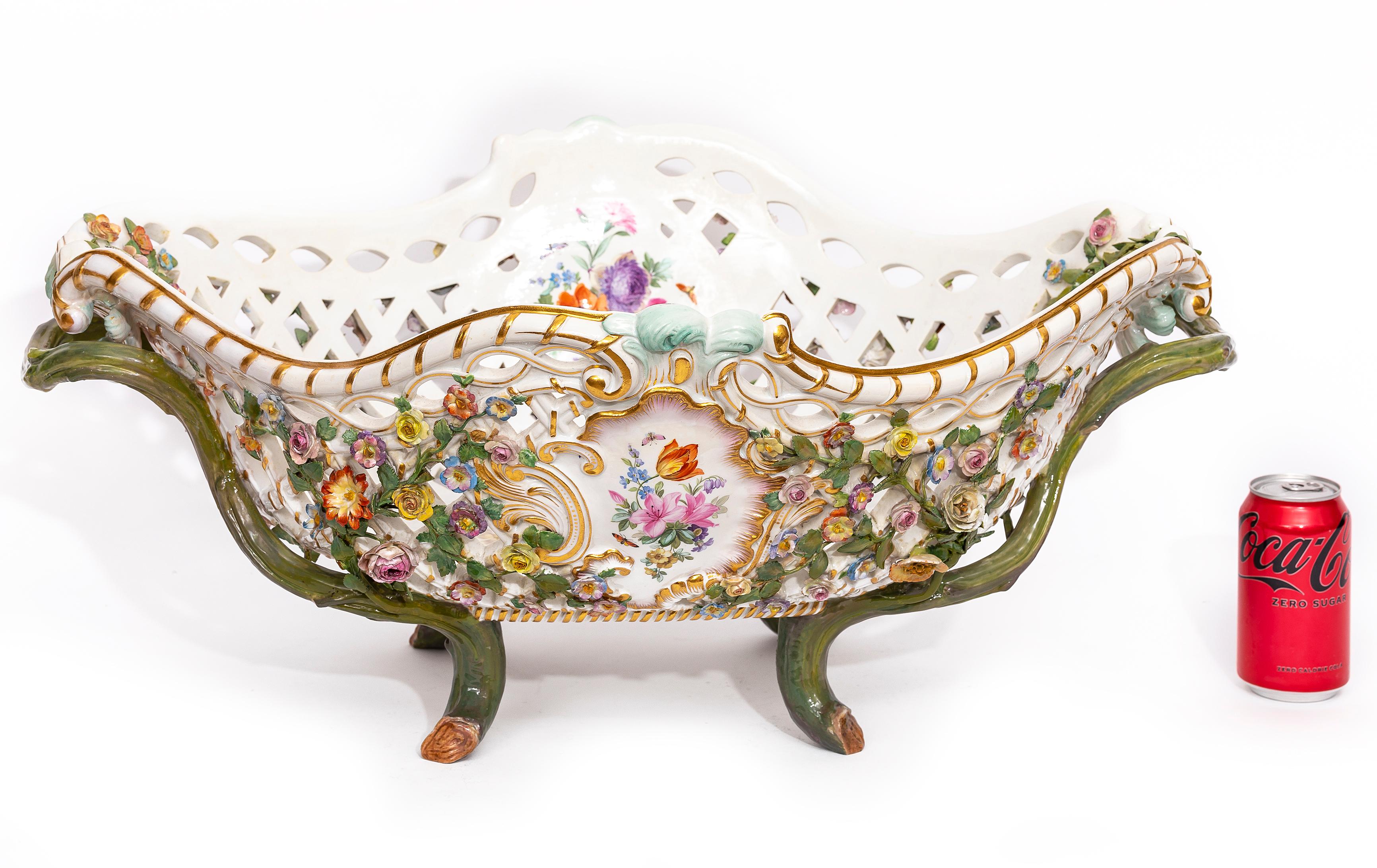 Monumentale centrotavola in filigrana traforata di Meissen Porcelain del XIX secolo con fiori in rilievo, manici a vite e decorazioni floreali dipinte. Il centrotavola presenta un intricato design a filigrana aperta e una decorazione floreale ricca