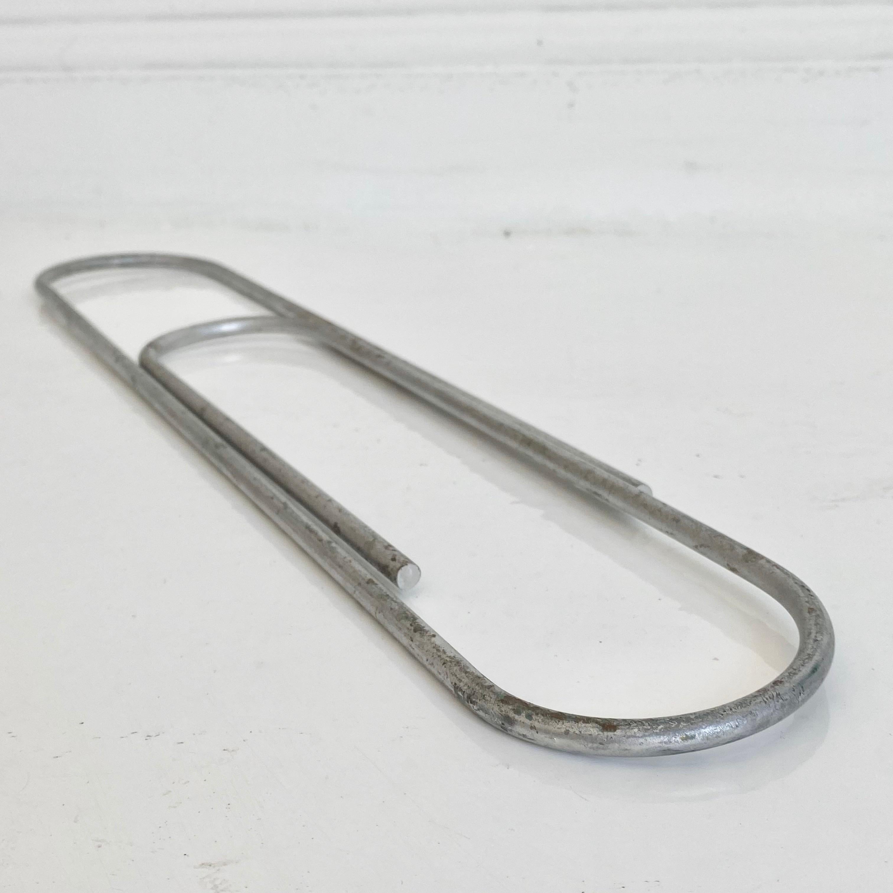 Giant metal paperclip slightly under 1.5 ft tall. Quirky accent piece or wall art. Good weight to object. Slight wear to metal exterior. Good vintage condition. Two available. Priced individually. Slightly different age/patina to both. 
 