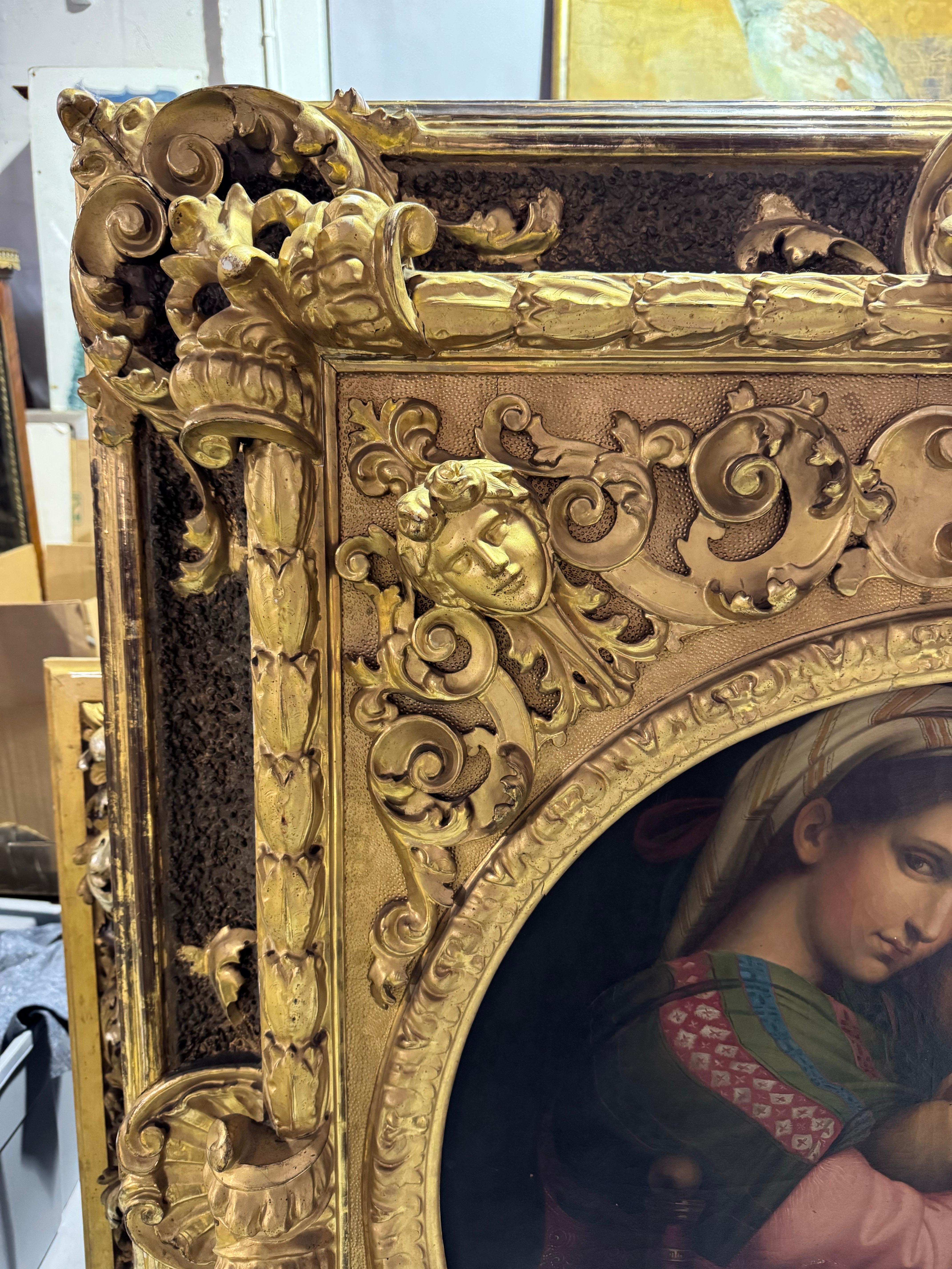 A monumental Italian mid-19th century ornately carved and gilded frame surrounds an oil on canvas signed painting, by listed artist E.Pieracinni. The frame is carved with elaborate scrolled acanthus leaves, and masks at each corner. The round