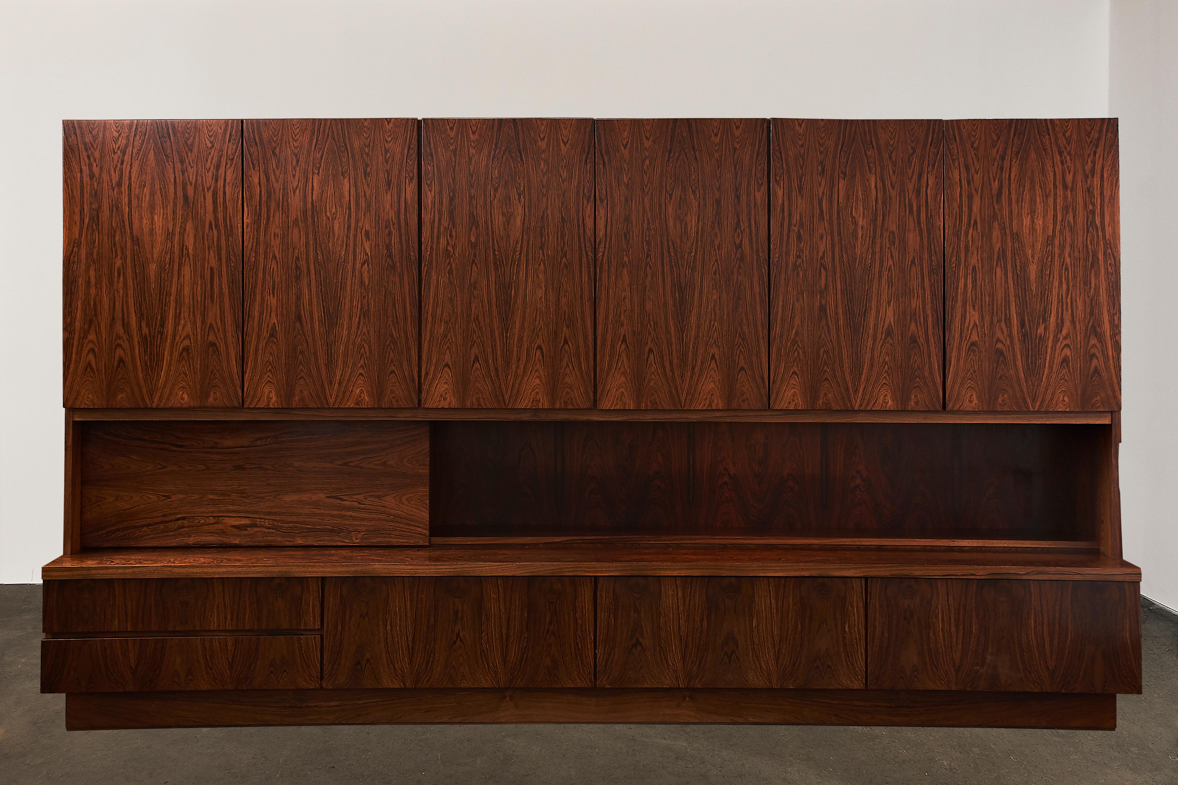 Monumental Mid-Century Modern wall unit with built-in bar, sideboard and myriad cabinetry.

Exceptionally beautiful cathedral cut and bookmatched rosewood. Interior compartments in tightly banded striped mahogany.

Highest quality craftsmanship
