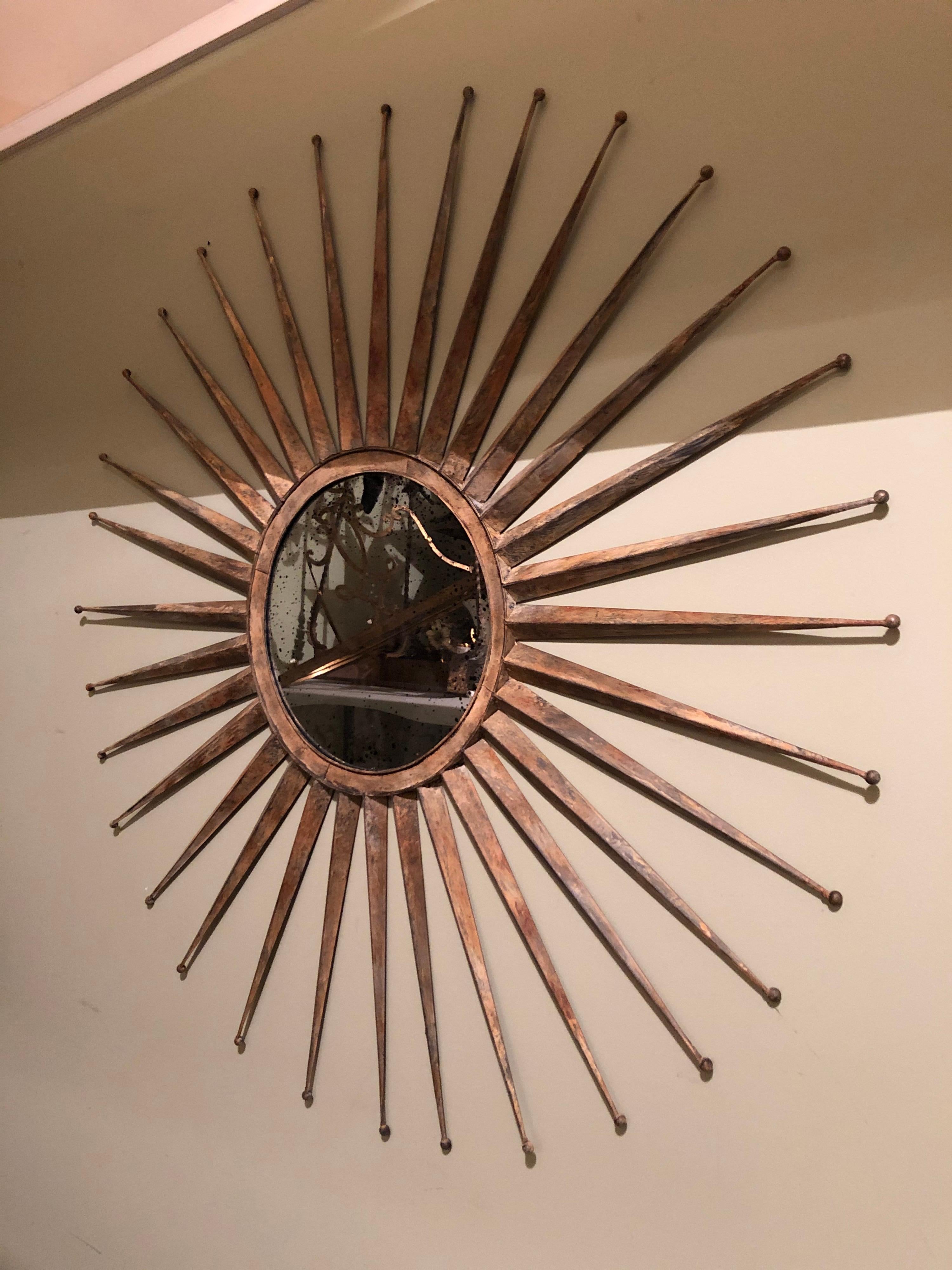 Monumental Mid Century rustic metal starburst mirror. Mirror has black speckled antiqued look to it. Starburst ends have little balls at the end. Actual mirror diameter itself is 13