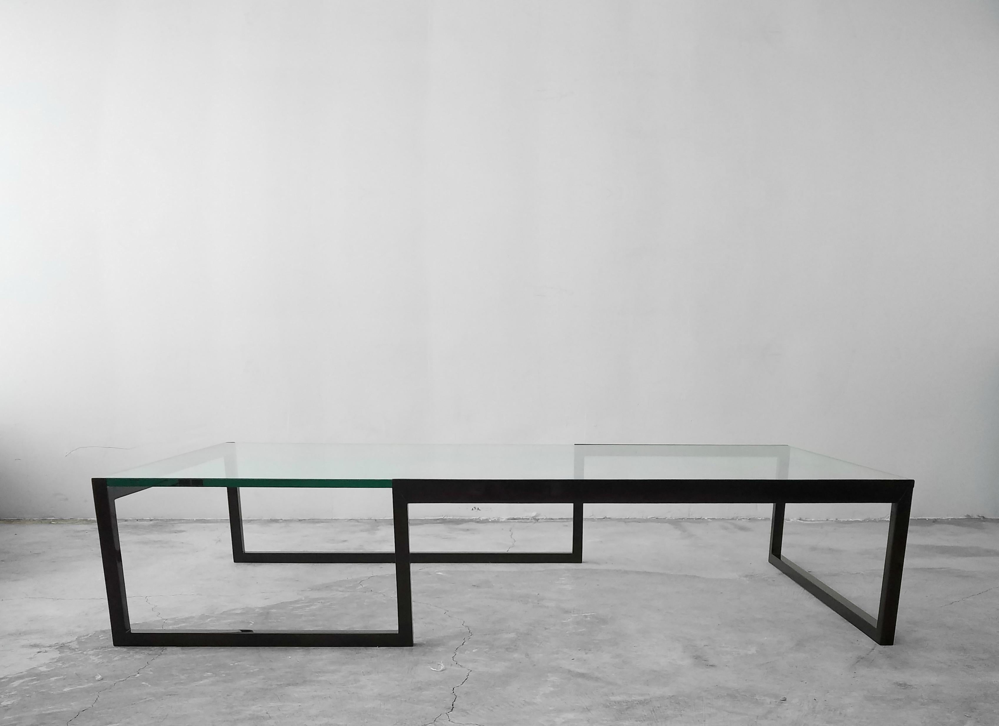 This is an extremely large and versatile metal and glass coffee table. The table frame is a unique shape and very minimal and modern in appearance. The frame has been lacquered, and under the lacquer is a wood grain, so it's a metal table that looks