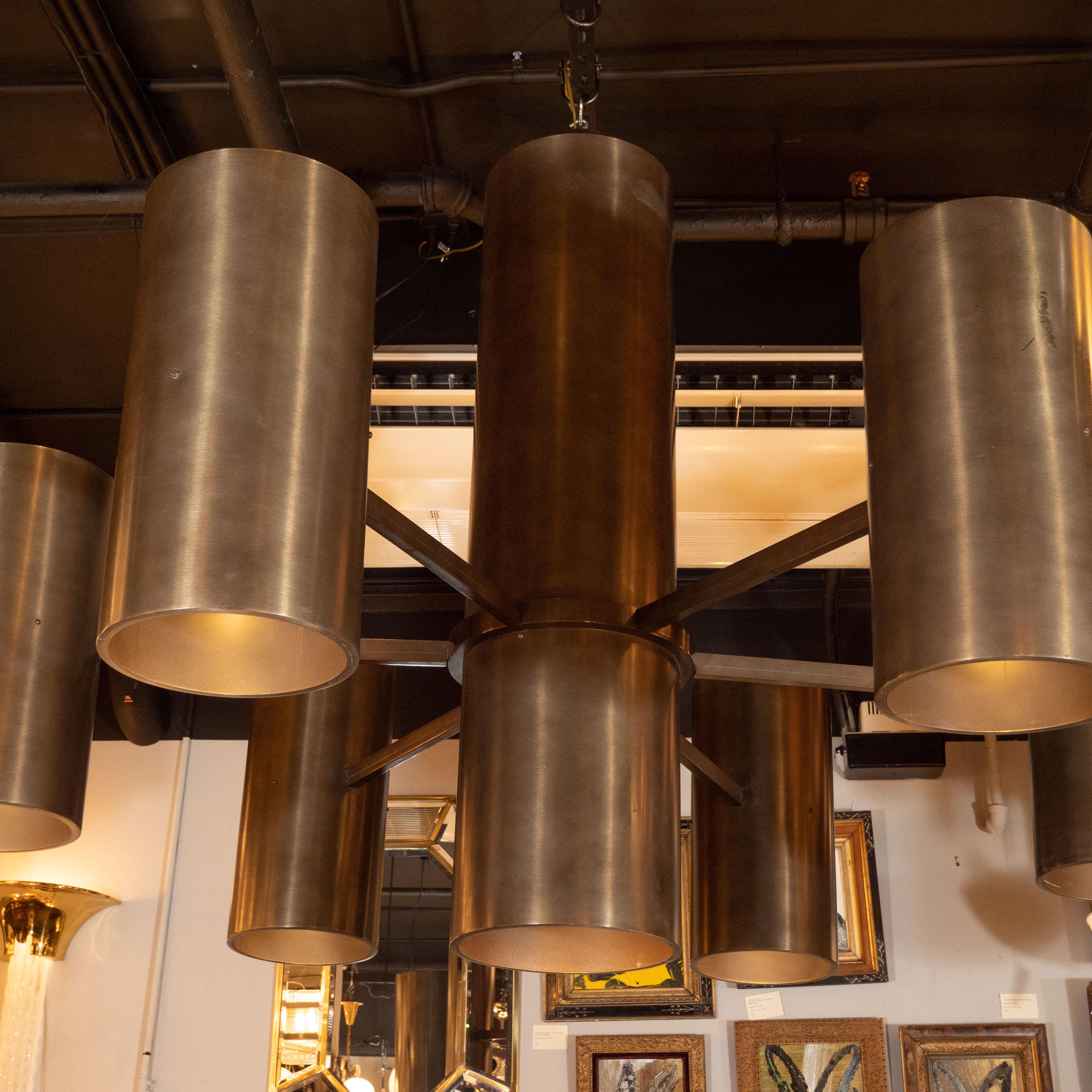 This impressive monumental Minimalist chandelier originally hung in the iconic Sea Cliff library in New York. It features six tubular shades emanating from a cylindrical body via rectangular supports all in oil rubbed bronze. Large scale, sleek and