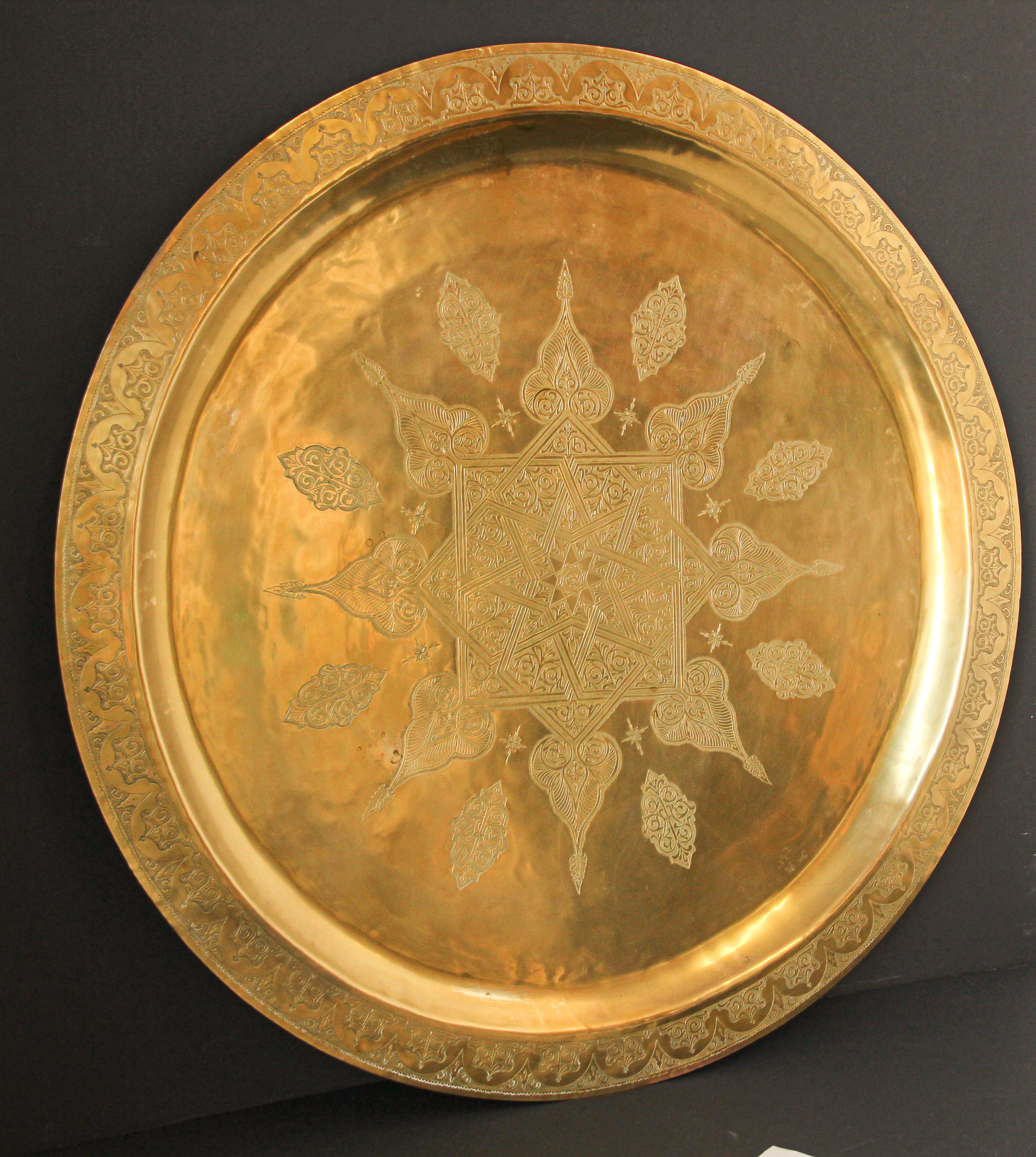 Monumental Moroccan metal brass tray platter.
Polished decorative metal brass tray with very fine intricate designs.
Finley hand-hammered and chiseled in floral and geometrical Moorish designs with a star in the middle.
Heavy brass metal brass tray