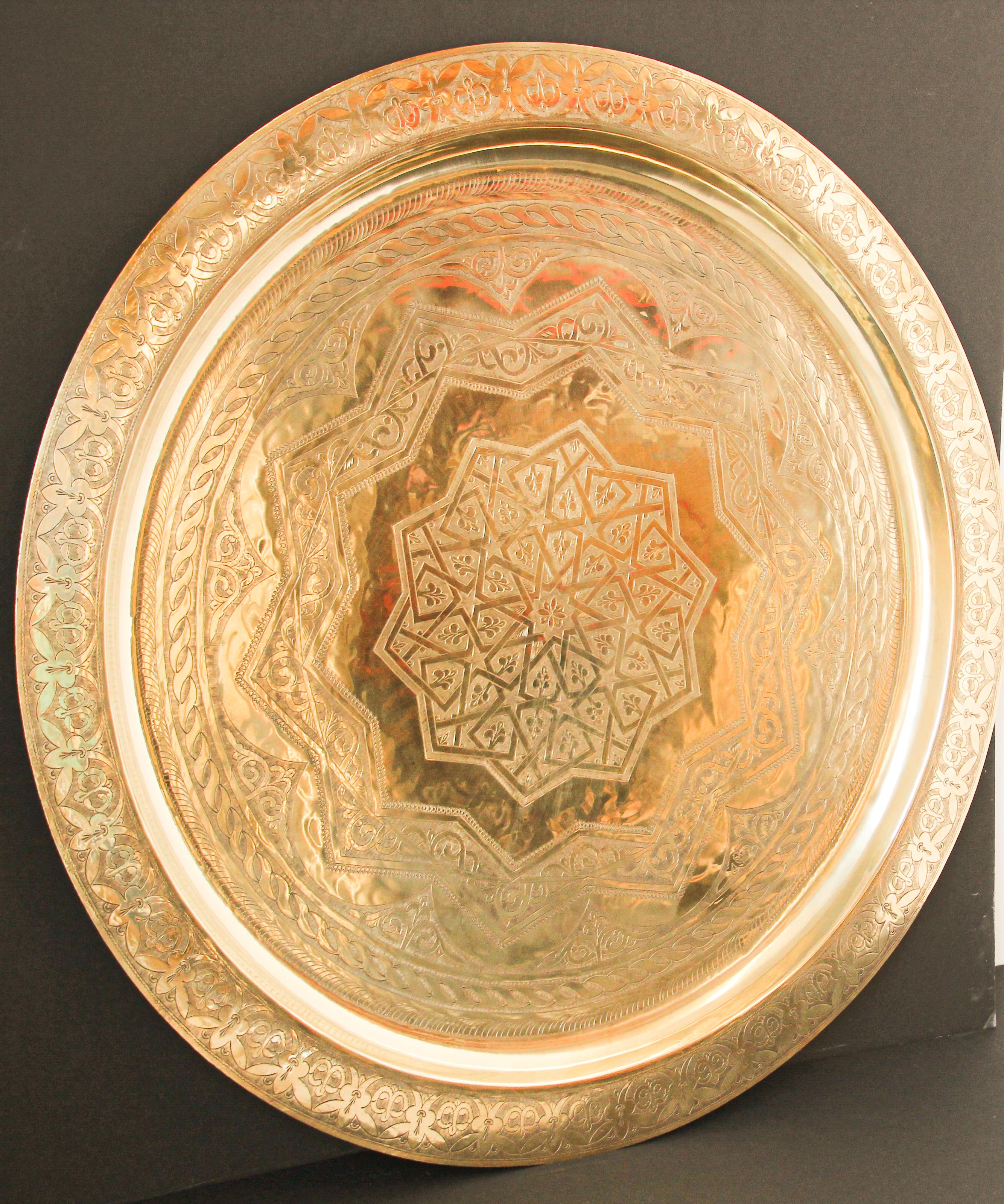 Monumental Moroccan metal polished brass tray platter.
Polished decorative metal brass tray with very fine intricate designs.
Hand-hammered and chiseled in floral Moorish style with a large lotus flower in the middle, pie crust border.
Heavy