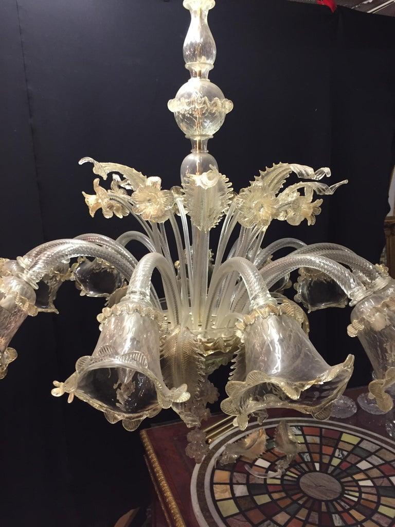 An monumental Italian Murano glass tulip form chandelier.
The lower pot or vase base having a stem flowing from the bottom with sprouting arms terminating in tulip forms each taking a single light bulb. Twelve lights. 
2 small acanthus leaves are
