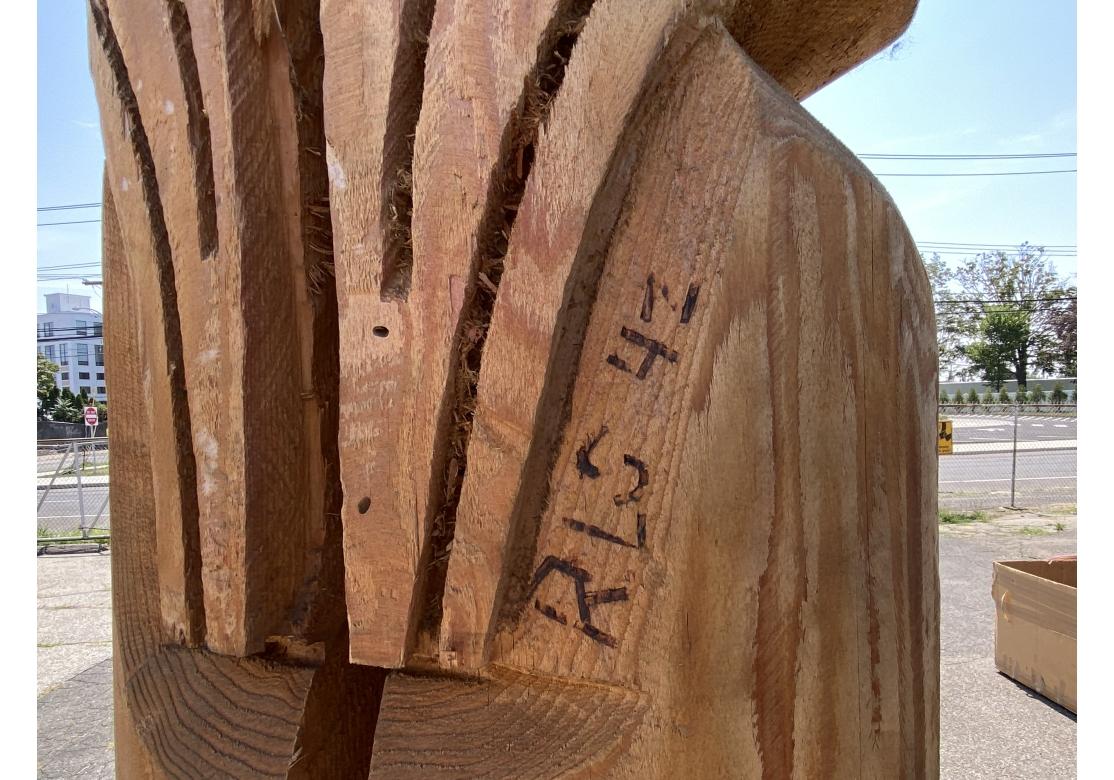 Tótem monumental tallado a mano que representa un ave alada sobre una figura y coronada por un zorro u oso que sostiene una presa de pescado. Pintado a mano predominantemente en tonos azules y blancos, el tótem monumental está construido con alas