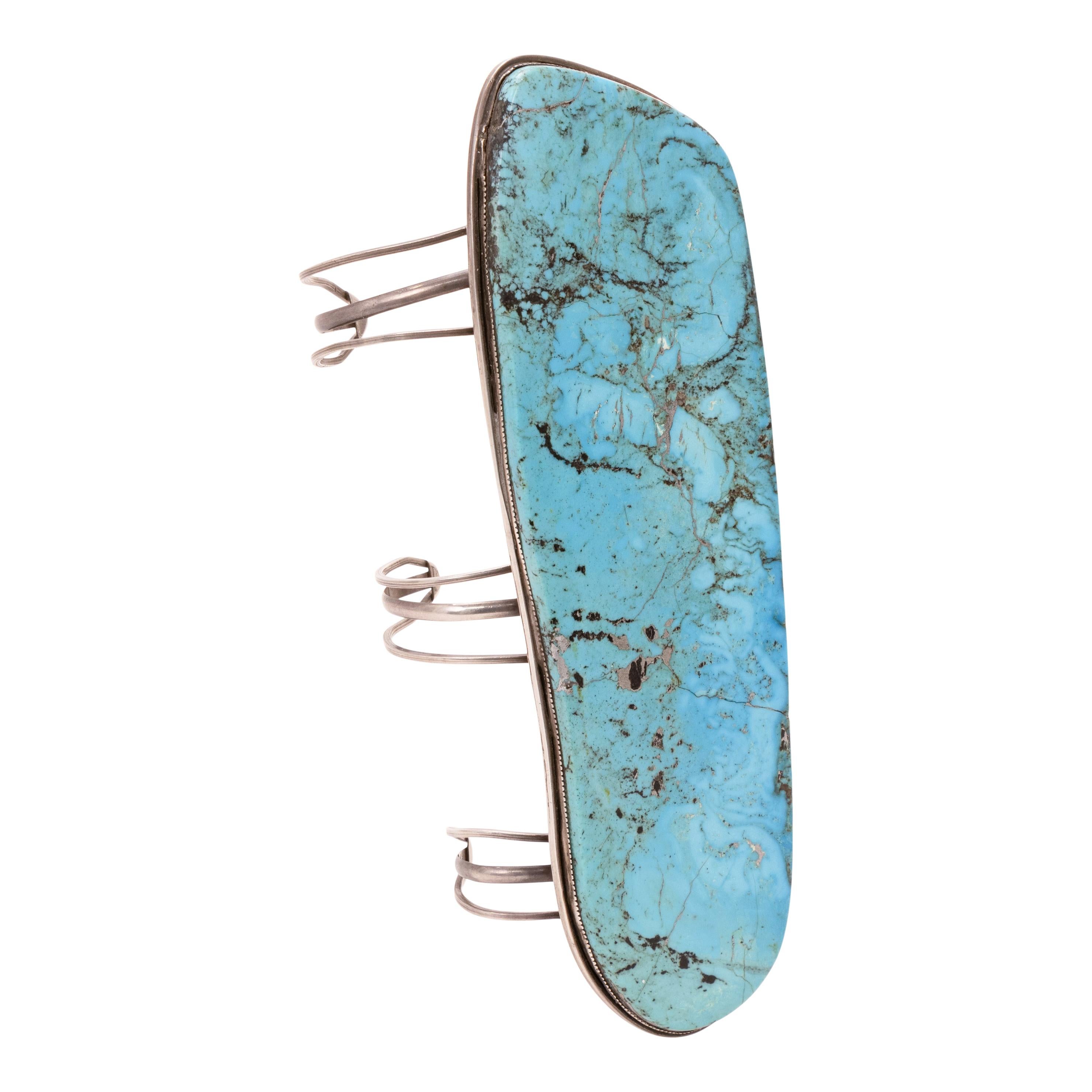 Bracciale monumentale in turchese Navajo. Bracciale in argento sterling con grande lastra singola di turchese incastonata su tre gambali spaccati. Lunghezza totale 9,5
