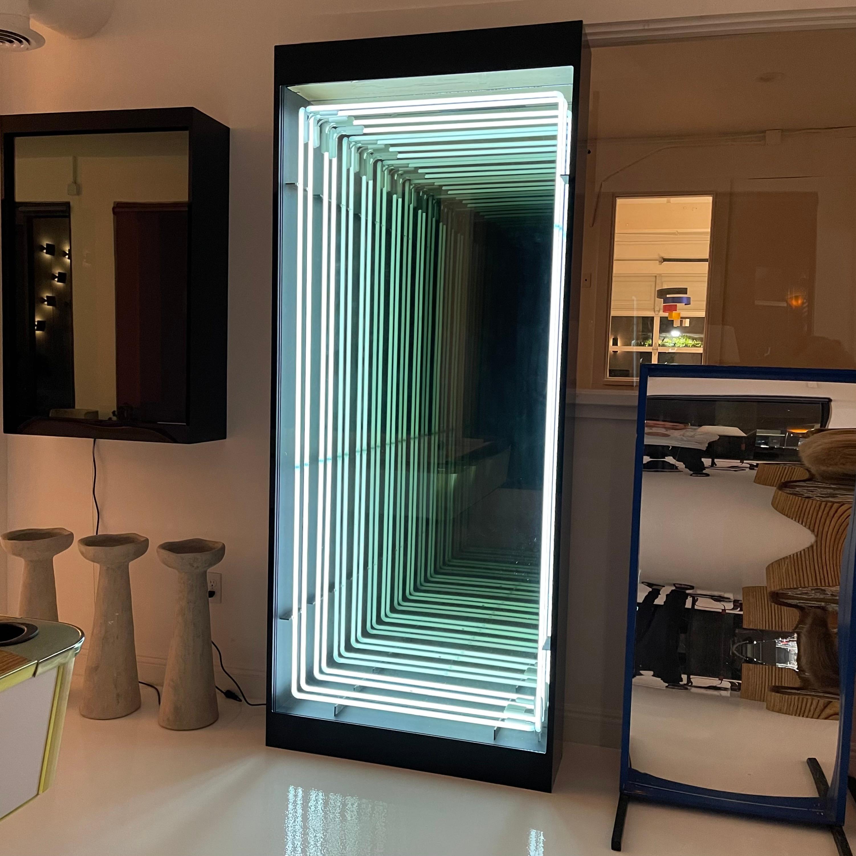 Monumental neon and plexiglass infinity mirror by Merit. Handmade in Los Angeles. Incredible presence with two white neon rings that reflect deep into the mirror. Great illusion. All encased in black plexiglass. Looks great during the day and even