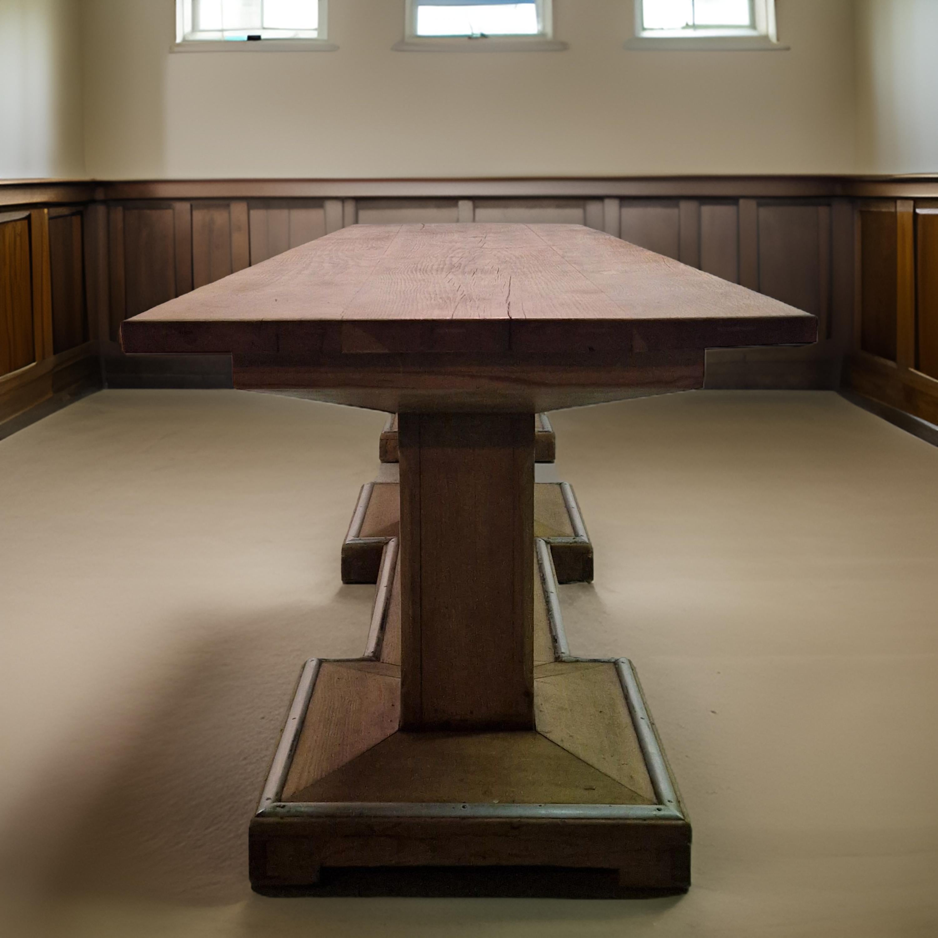 This exceptionally large table has a solid oak top that sits on a, one piece, three column base. The top is 4cm thick. The base has a metal foot guard all around.
Considering the age and use of the table, it is still in very good condition. The top