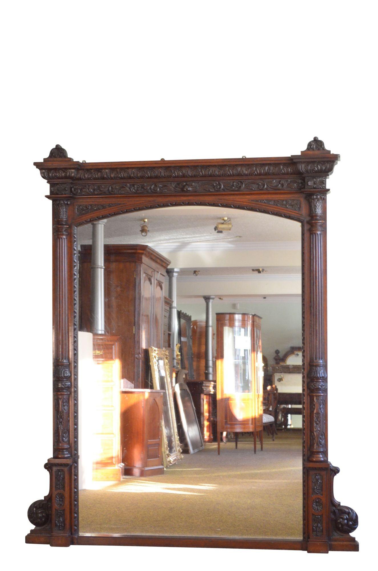 P0277 A monumental 19th century solid oak mirror, having foliage carved cavetto cornice with decorative carved bell shaped finials above acanthus leaf carved frieze and egg and dart carved inner edge enclosing original glass with some foxing, all