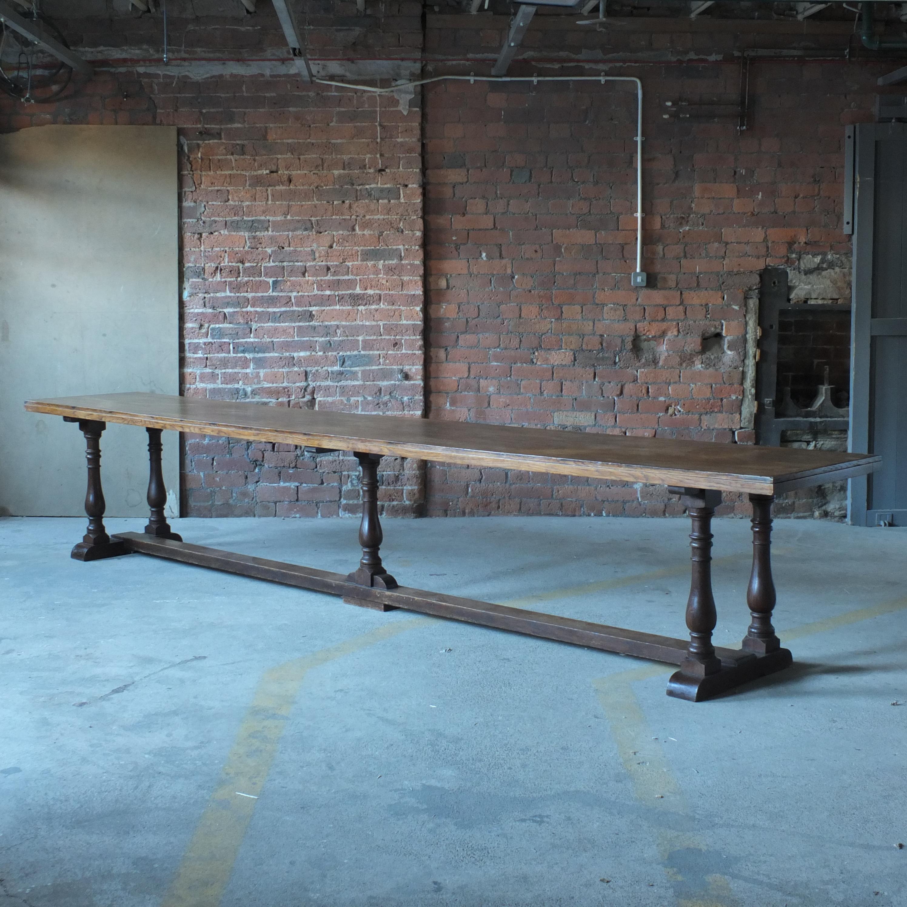 A huge early 20th century oak refectory table on turned column legs joined by a thick oak stretcher. The top is oak veneer with some minor losses but overall clean and tidy with no large marks or scratches. At over 4 meters long this table should
