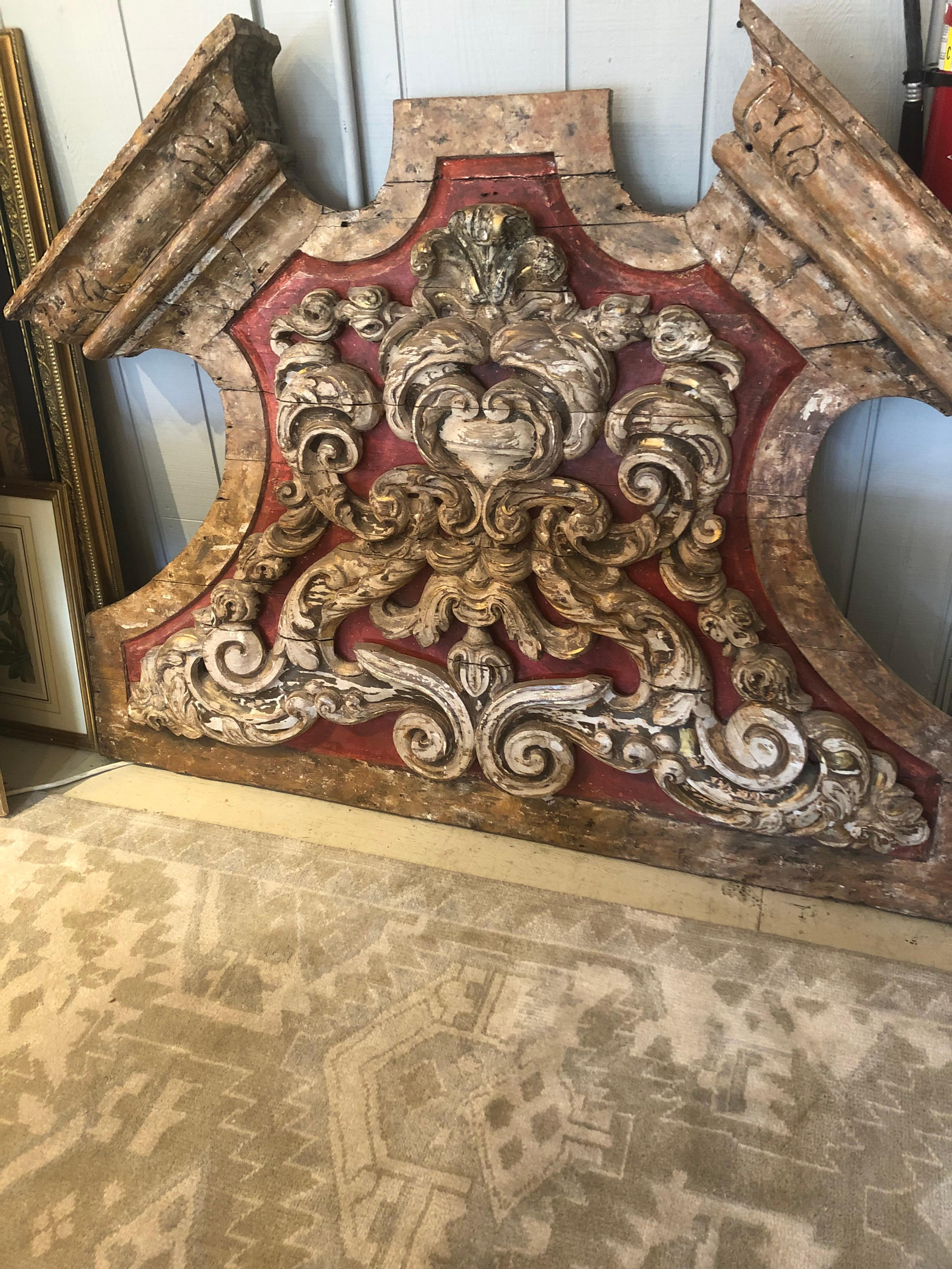 A strikingly large and ornate fantastic 19th century one of a kind architectural fragment from a French monastery having red painted weathered background and sculptural 3 dimensional raised carved wood decoration. Makes a monumental statement in
