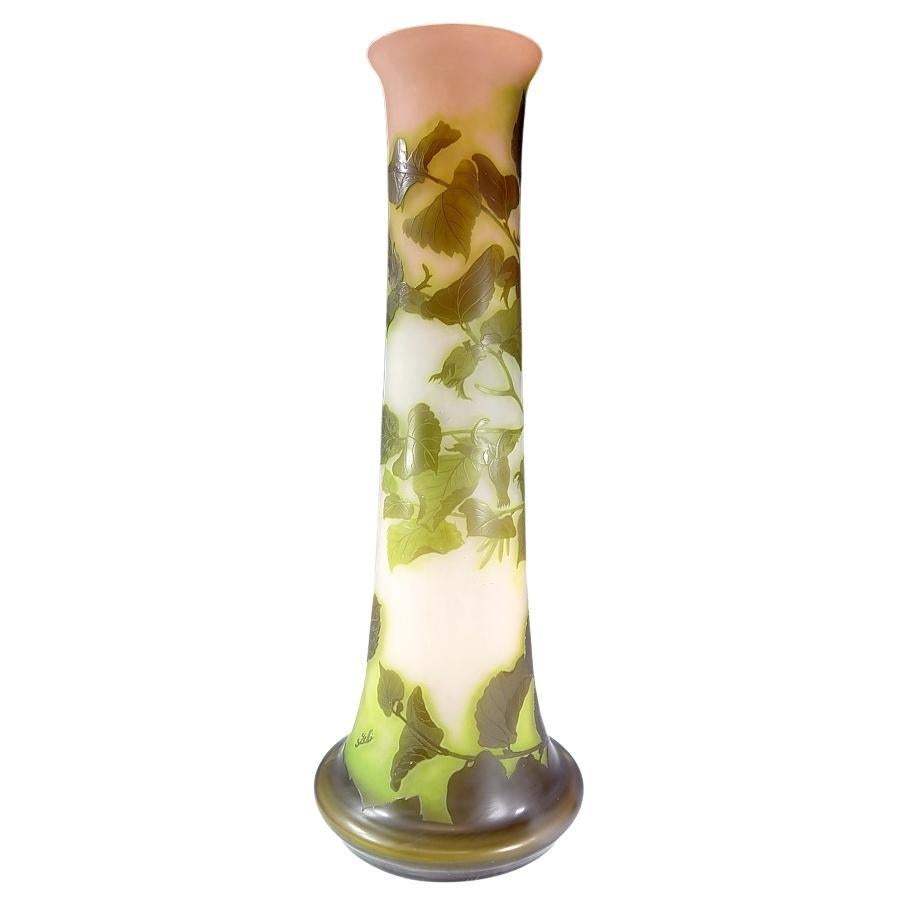 Ce grand vase d'art en verre camée de Galle présente un motif floral et de feuillage gravé à l'acide dans des couches de verre vert olive, vert clair, blanc et rose. L'intérieur du vase est recouvert d'un revêtement en verre émaillé qui a été cuit