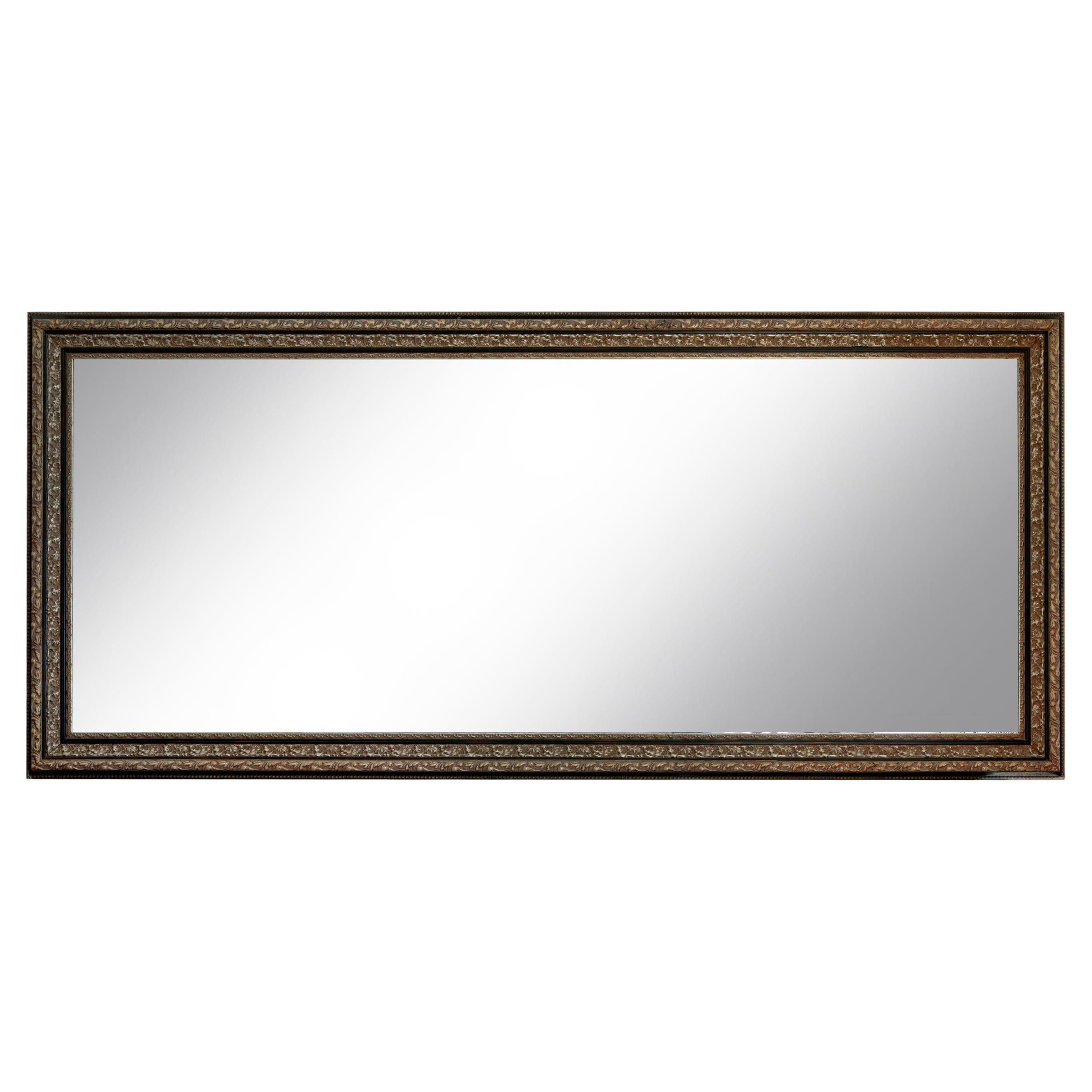 A monumental rectangular silver leaf gilt & carved wood mirror. The long narrow rectangle mirror has a beautiful carved frame. An important piece for a grand space as a standing floor mirror or horizontally above a fireplace or credenza. The