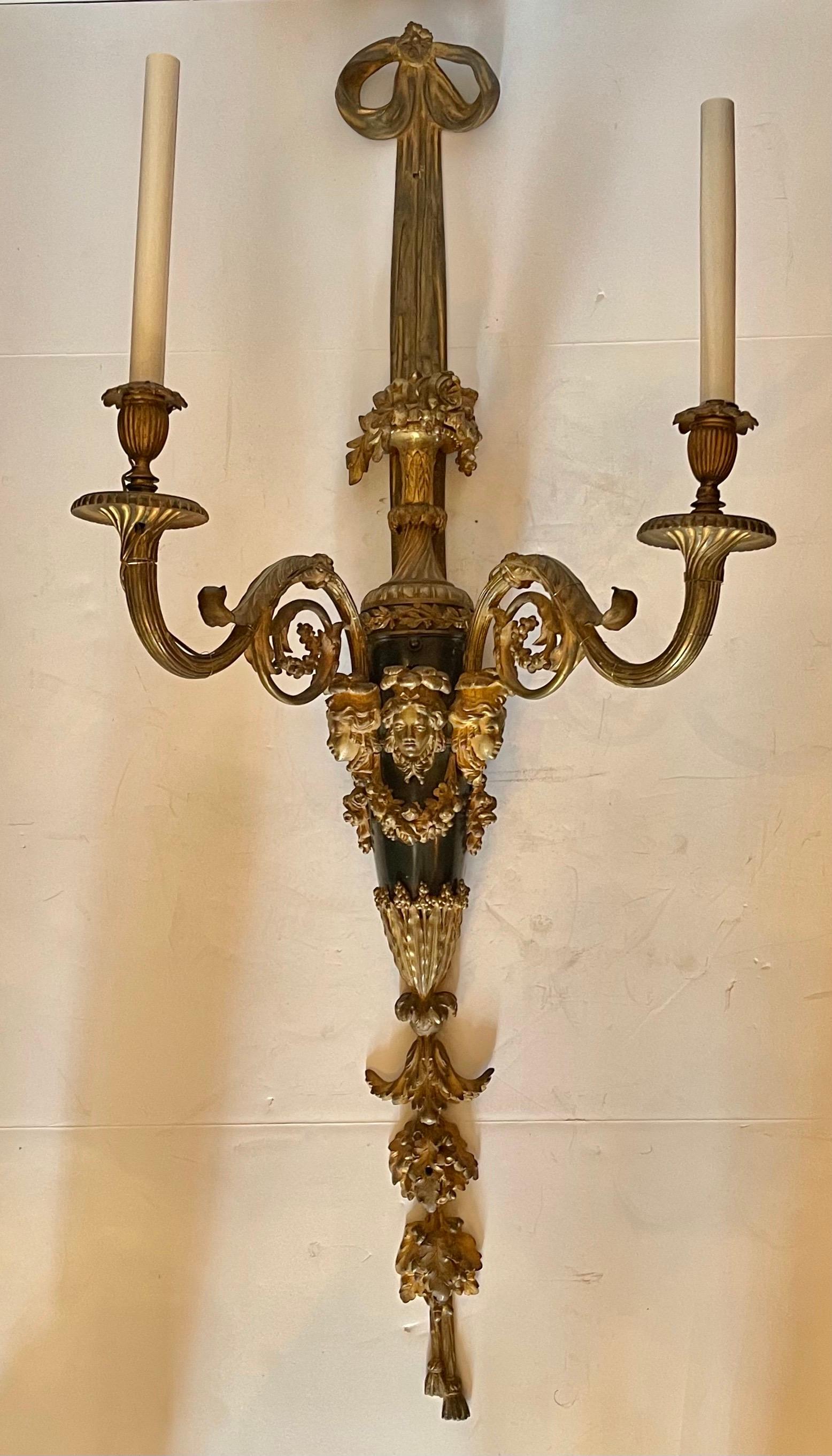 Merveilleuse paire d'appliques en bronze doré et patiné, de style Louis XVI. Ces appliques de taille monumentale et opulentes, ont 2 lumières de candélabre chacune avec des cannelures torsadées composées, des acanthes et des grappes de fruits. La