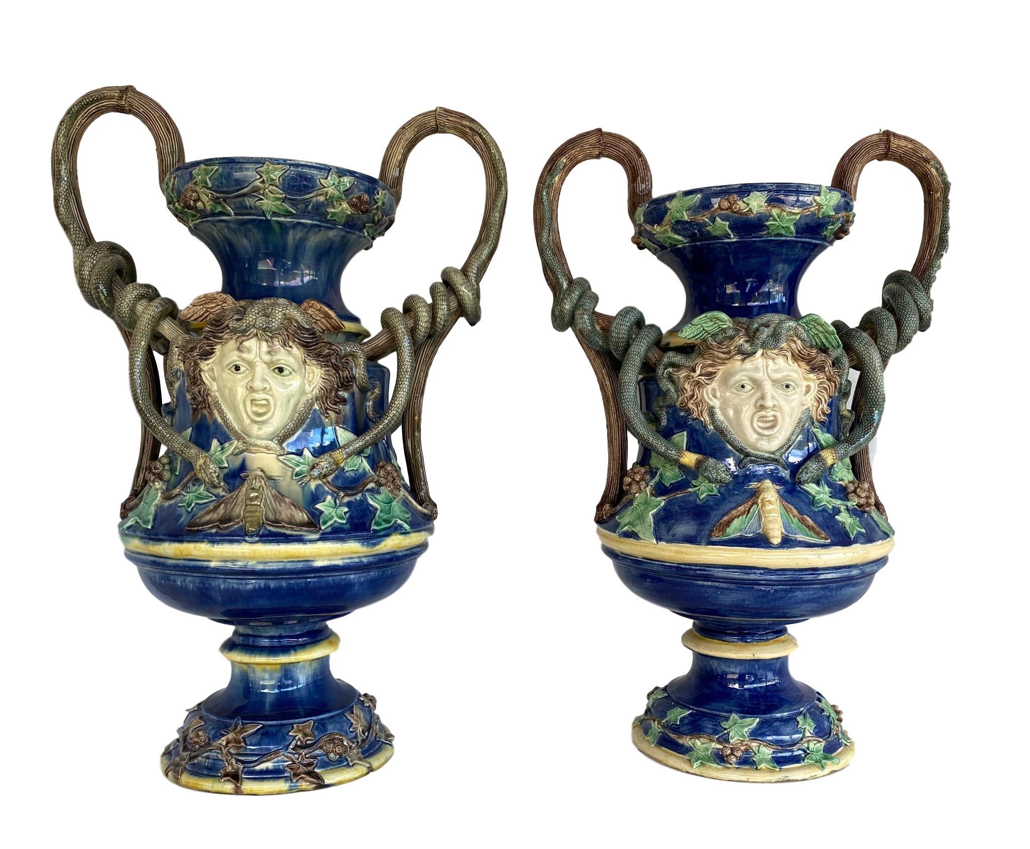 Monumental pair of Majolica Palissy Cobalt blue ground Medusa vases, School of Paris, circa 1870, each of waisted cylindrical form, with snakes coiled on the simulated branch handles, with snakes encircling the head of Medusa, with further snakes in