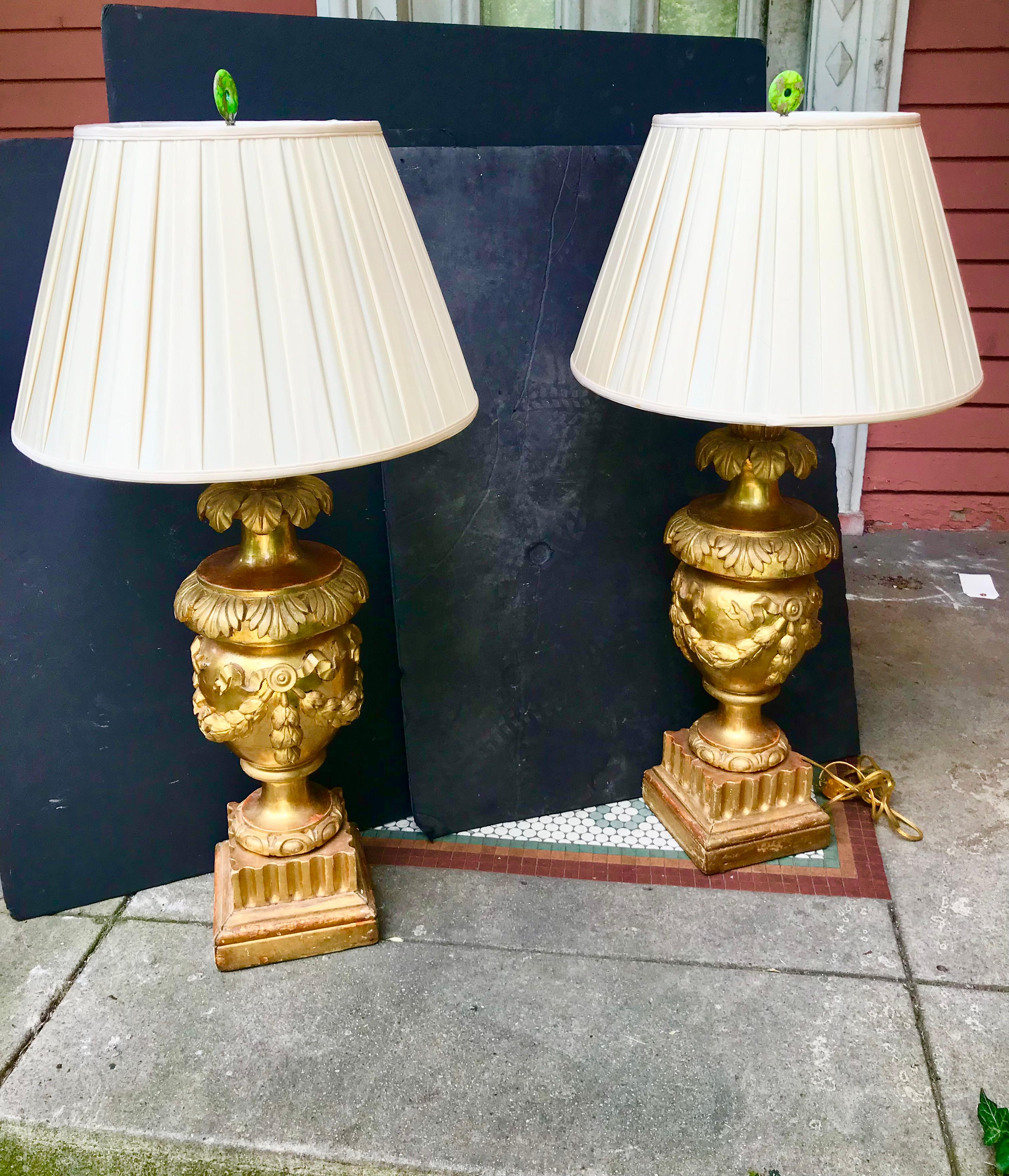 These are shippable via UPS ,ignore existing 1stdibs quote and request new ground quote .Very large pair of giltwood urns now converted to lamps (snip of scissors and just urns again). Decorated with ribbons, flutes, floral and foliate motifs in the