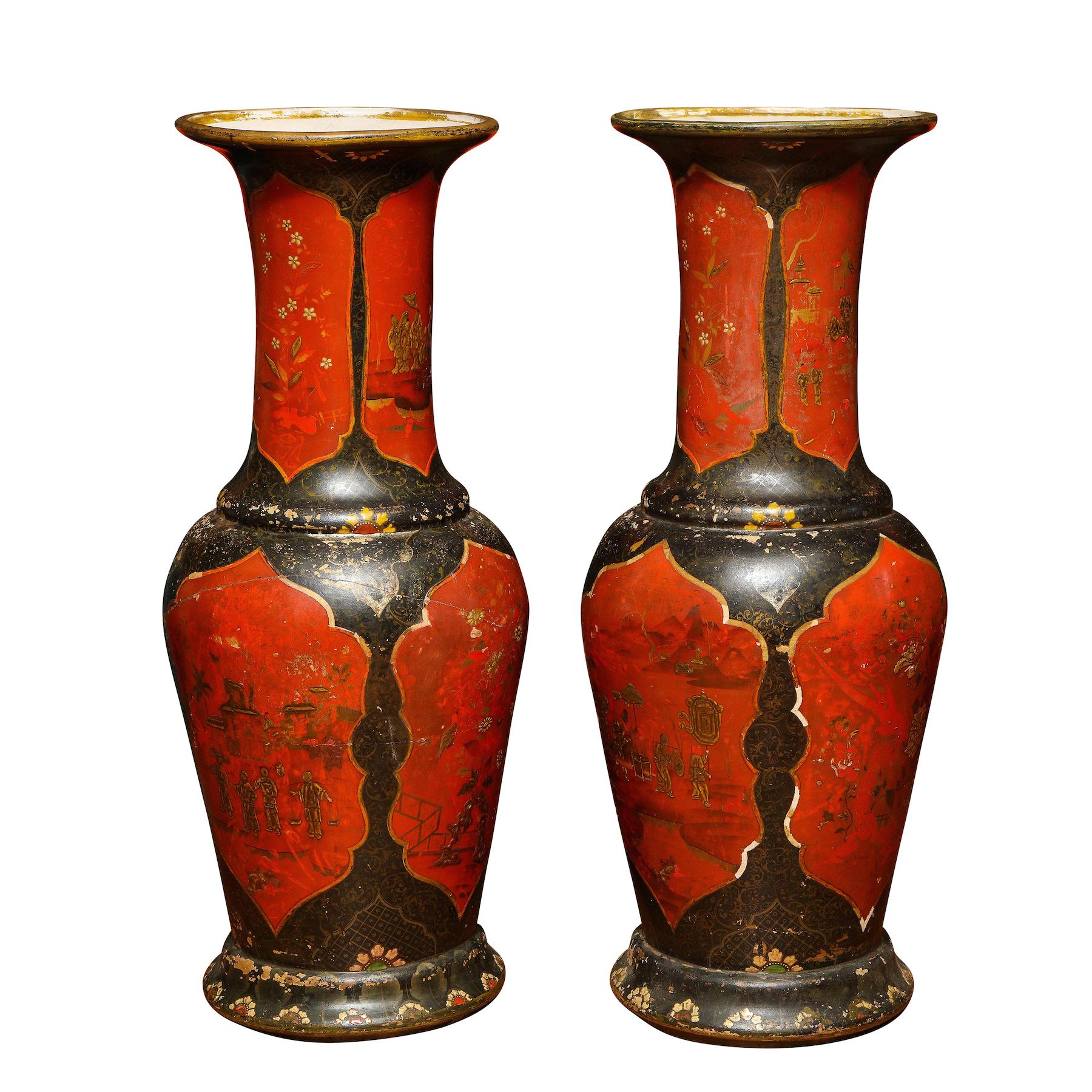 The surface 'japanned' in imitation of Chinese lacquer in red and black, of baluster form with a slightly spreading foot, the enamel decoration formed of panels of chinoiserie figures at various pursuits, reserved on a black-ground with gilt
