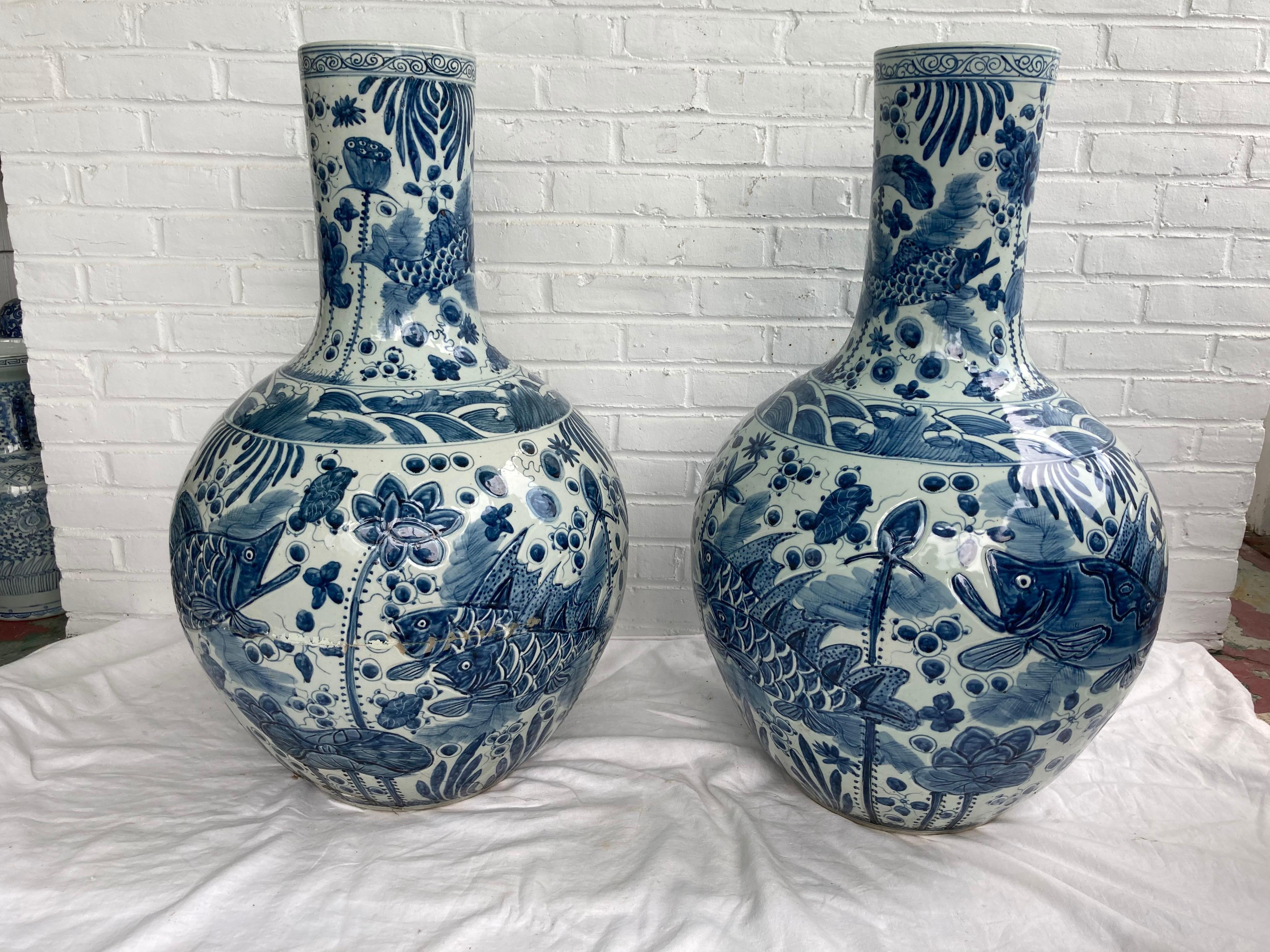 Very large pair of Chinese blue and white vases depicting fish... one with cracked base and repair work.... the other in great condition.... the pair is priced as a pair and priced accordingly with one repaired.... but looks great if turned!
