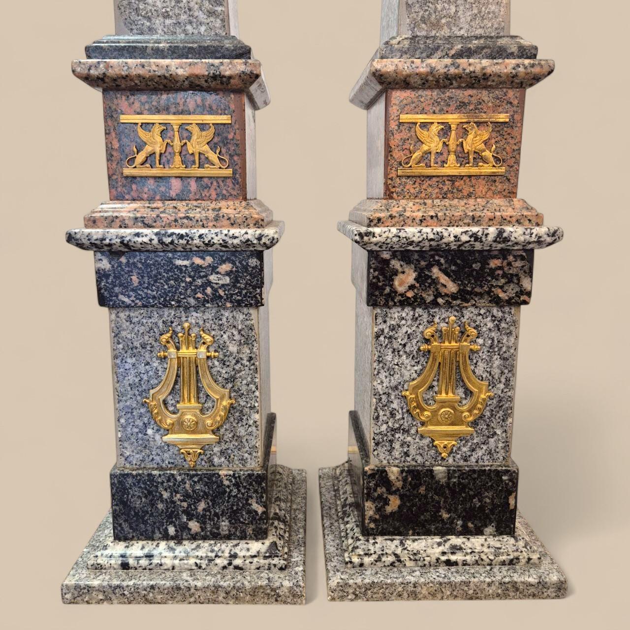 Monumental in both presence and elegance, this exceptional pair of obelisks reaches an impressive 99 cm in height, immediately affirming their rarity and decorative power. Crafted from porphyry and granite in subtly contrasting tones, they feature