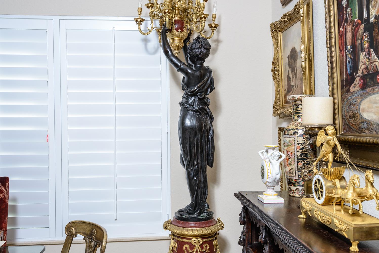 Fit for a palace, this monumental pair of Torchères have almost lifesize patinated bronze female figures standing on red marble pedestals adorned with ormolu flower garlands standing on Lion’s feetand are holding twelve light ormolu Candelabra. They
