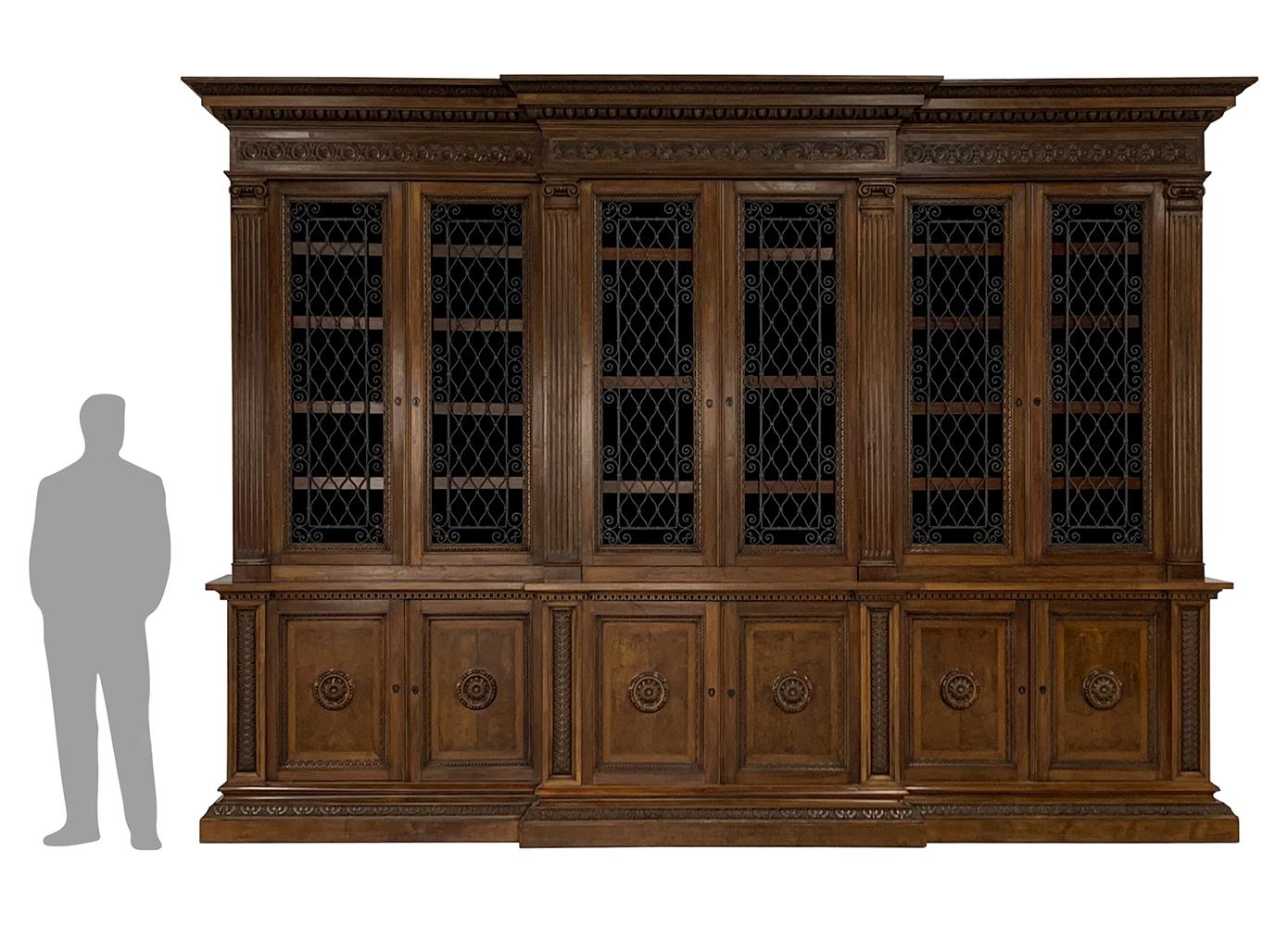 Each designed with a base containing four double closed doors with crisply carved circular medallions in the center. The top containing four double doors designed with exquisite hand forged iron grill panels below a heavy crown mould of shells,
