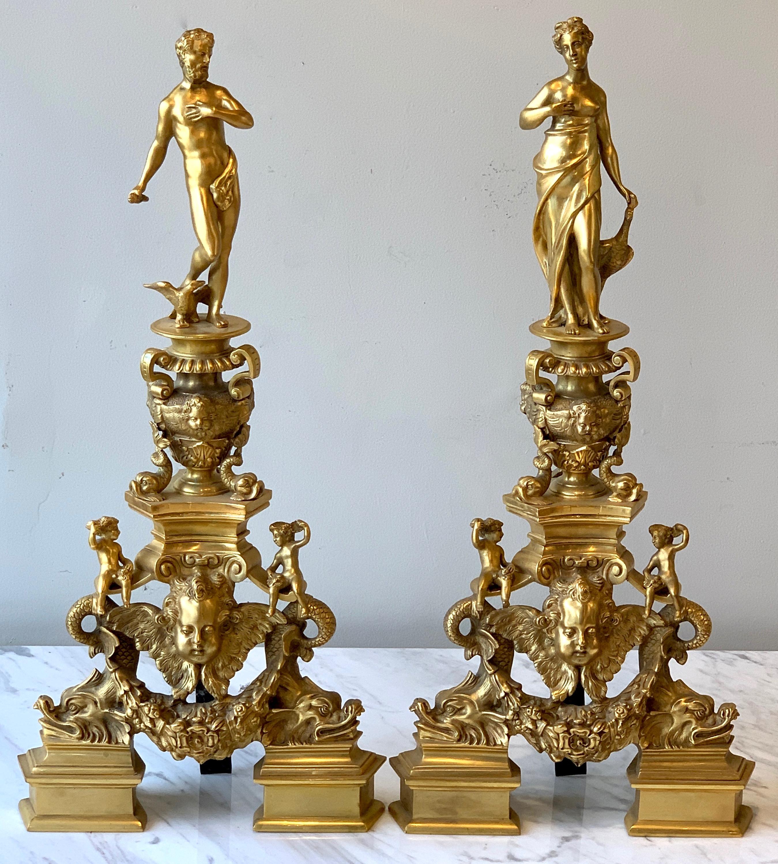 Large mirrored pair of French gilt bronze figural chenets or andirons featuring classicaly inspired dolphins, cherubs, urns and figures.