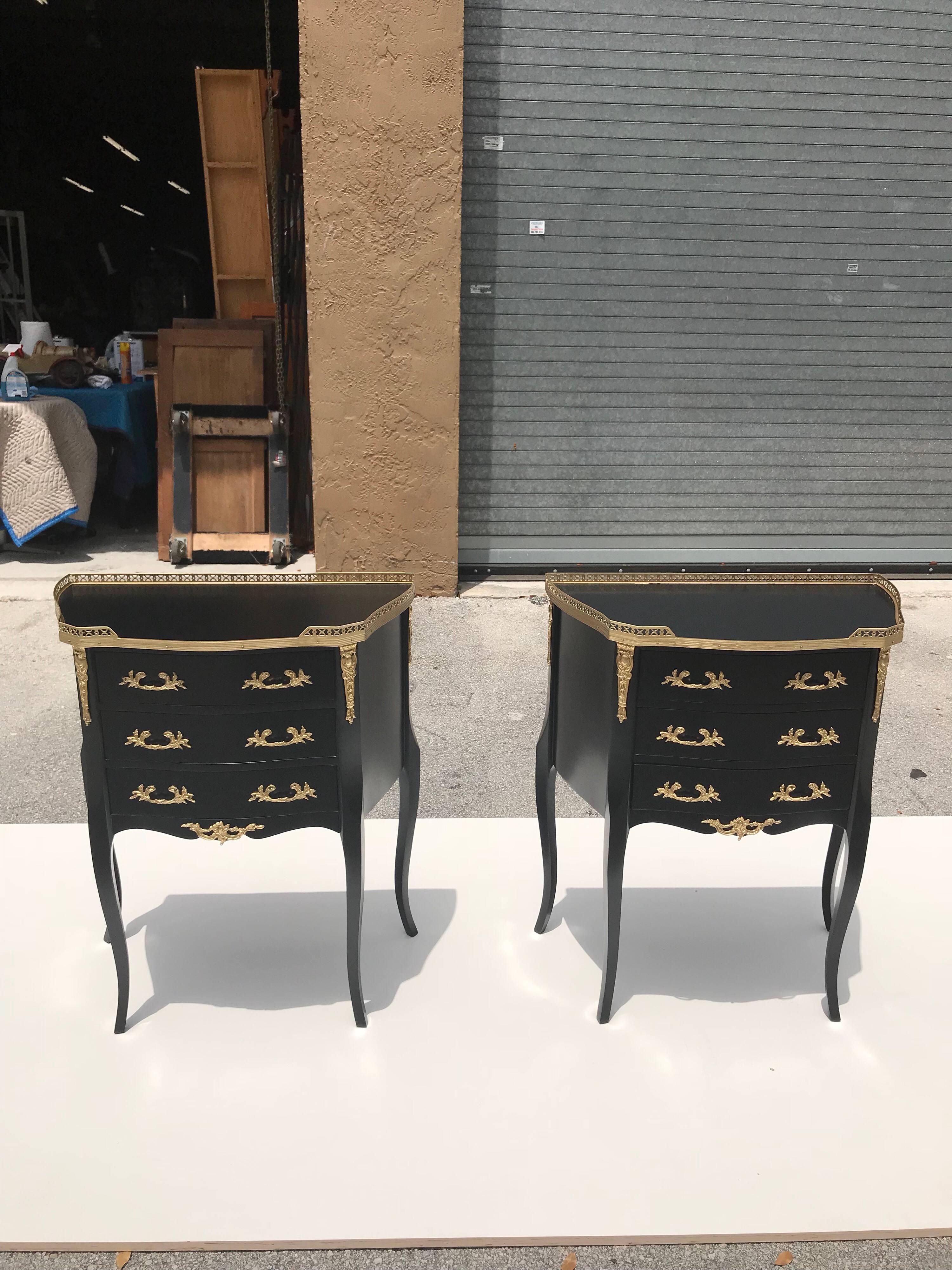 Monumental pair of French Louis XVI ebonized nightstands by Maison Jansen. This pair of Louis XVI bedside commodes or side table is composed of ebonized wood with bronze hardware detail, three drawers and four Sabre legs. The pair of nightstand are