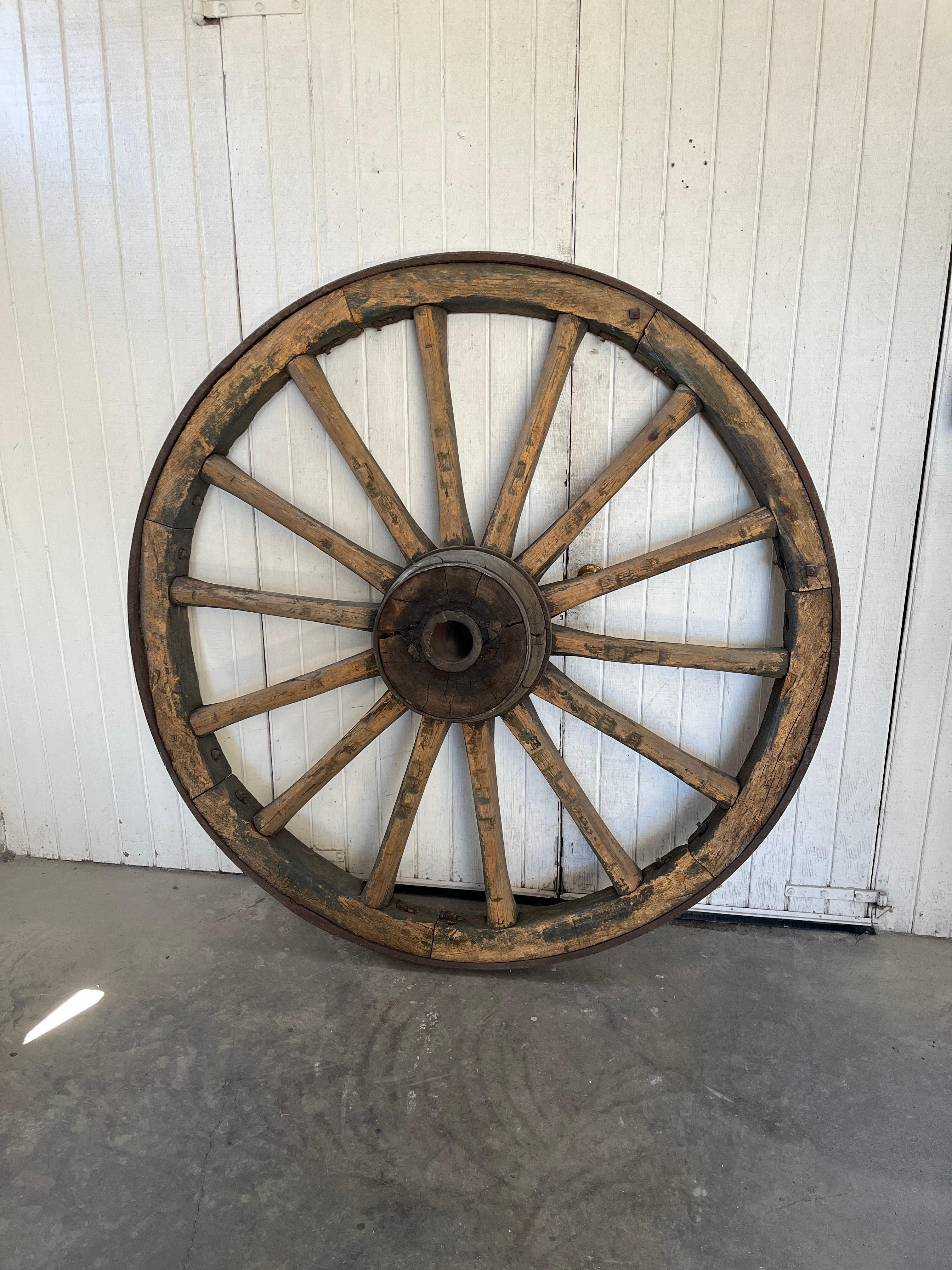 Oversized Antique French Wagon Wheels– late 18th Century Farm Relic This weathered oak and iron wagon wheel originates from rural France and evokes the craftsmanship and endurance of pre-industrial agricultural life. Its rich patina, timeworn
