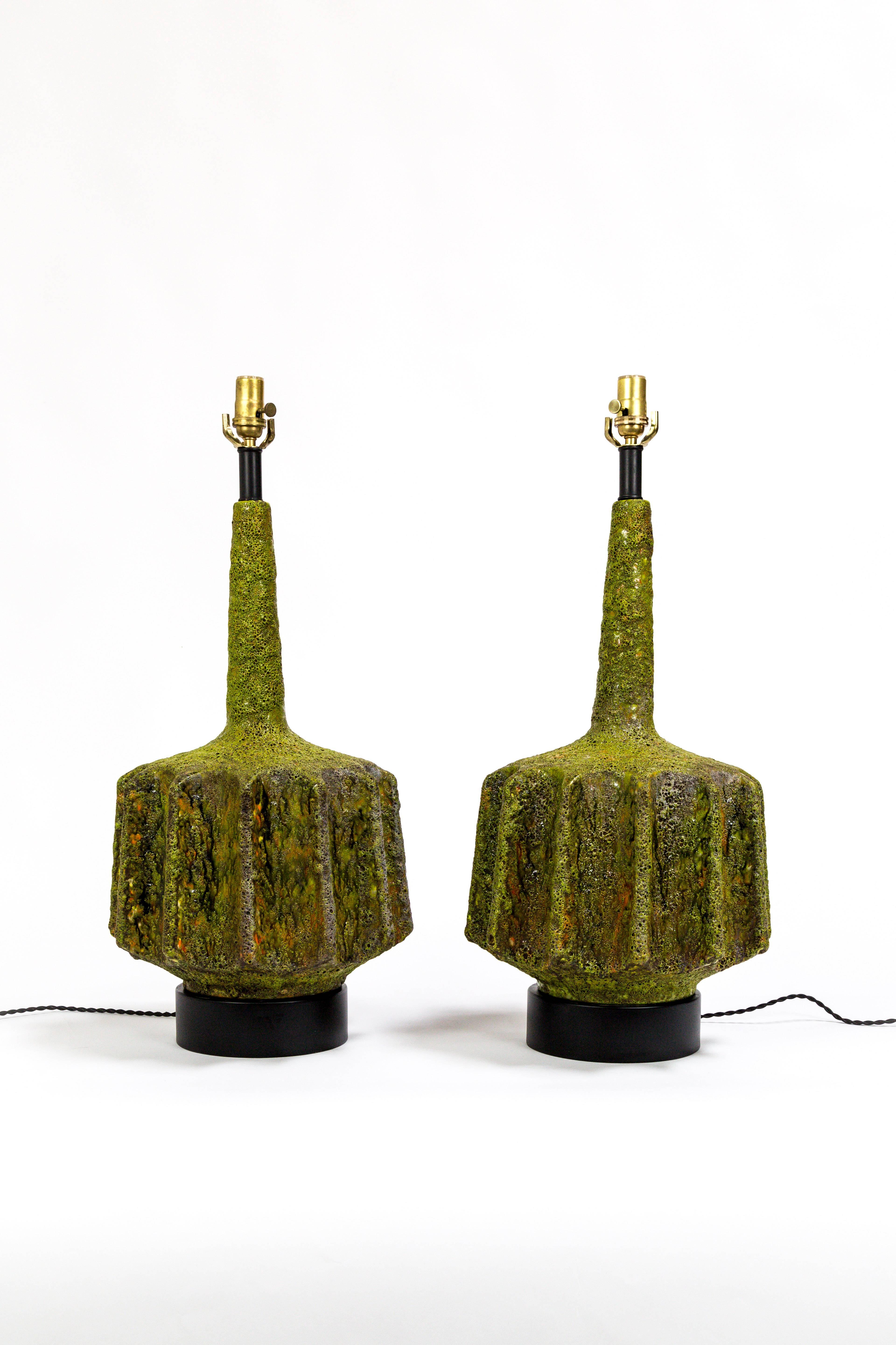 These striking lamps were designed by Marcello Fantoni; a beautiful shape with scalloped sides.  Monumental, fat lava glazed ceramic in multifaceted green with hints of orange and yellow.  Newly wired with black, rayon covered twisted cord.  Italy,