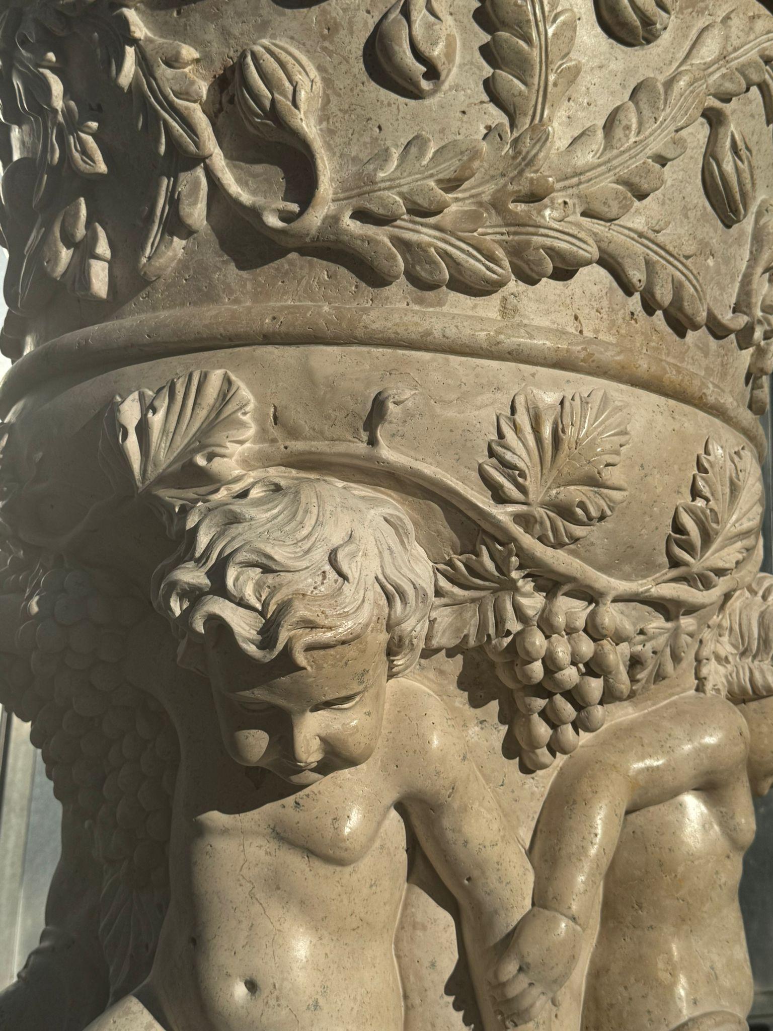 Stunning and monumental pair of Italian marble urns, finely hand-carved in the 20th century. These grand vases are richly decorated with high-relief cherubs (putti) and intricate ornamental motifs throughout, showcasing exceptional craftsmanship and