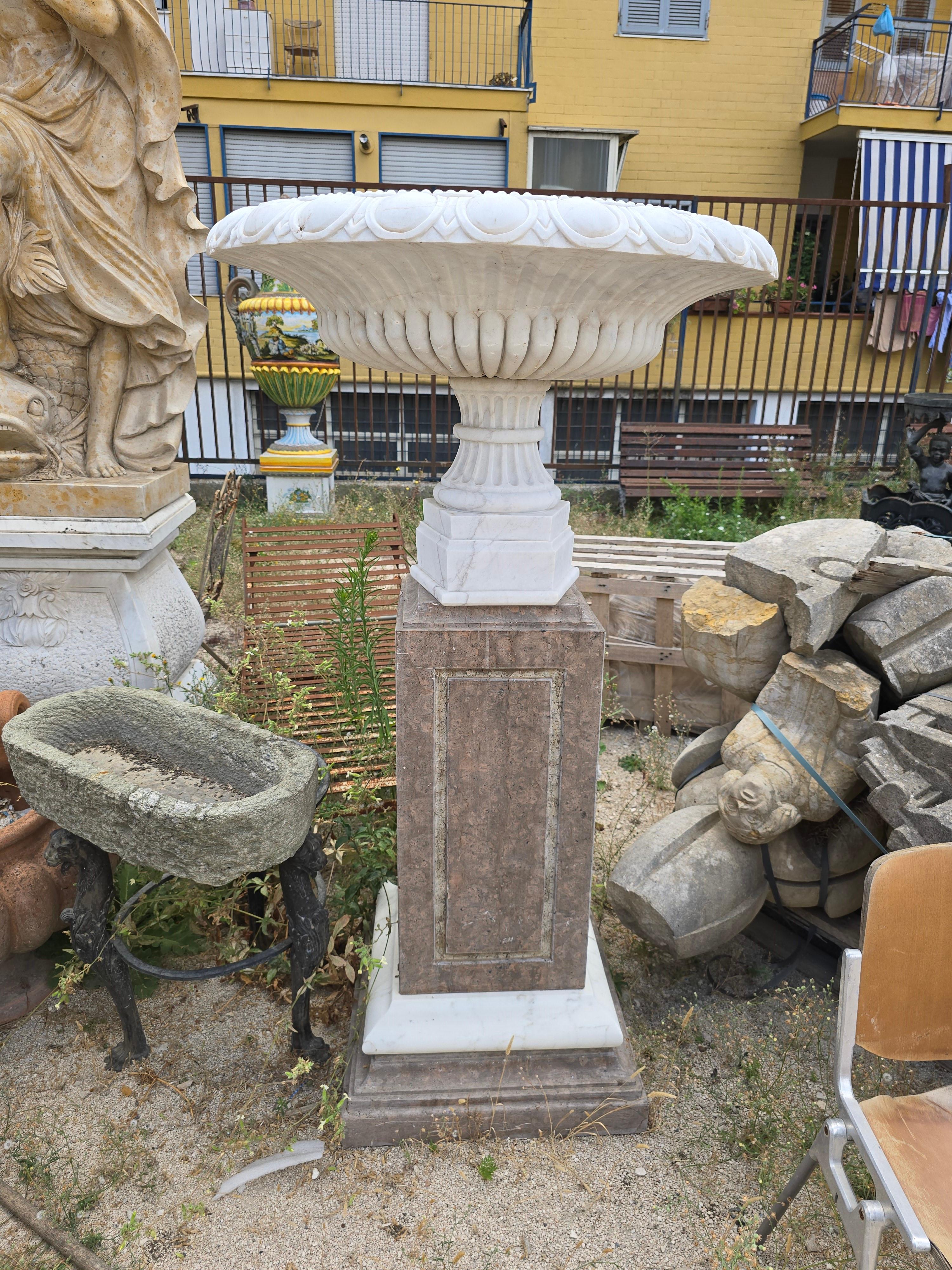 Exceptional and monumental pair of Italian marble urns, masterfully carved and turned across their entire surface. Executed in the Roman classical style, each urn features deep fluting around the upper body and a striking central medallion depicting