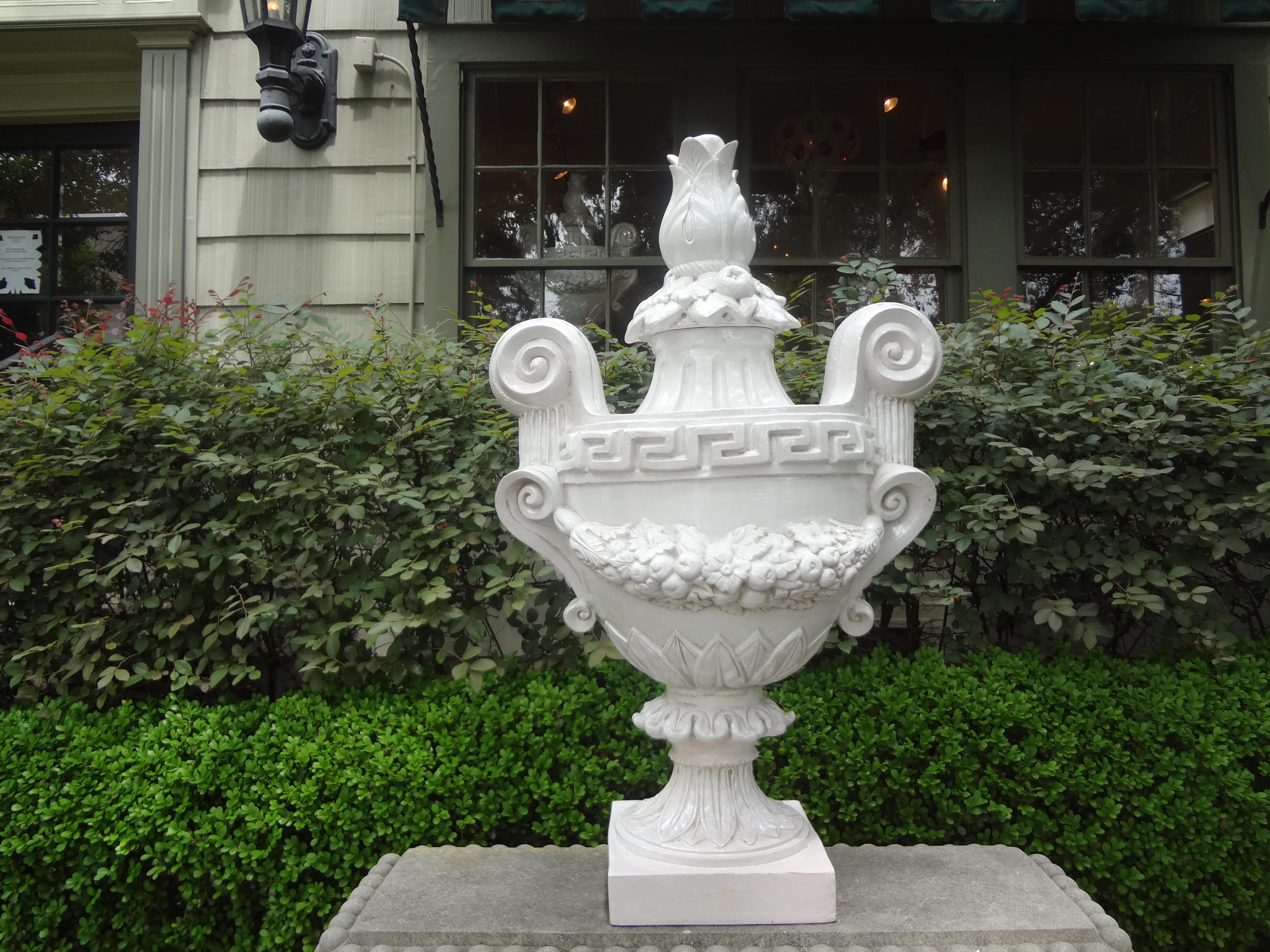 Monumental pair of Italian neoclassical style white glazed terracotta urns with fruit and floral swags and a Greek key design. These magnificent urns come in two parts, the bases and the lids. These stunning large scale urns measure: 37.5 inches in