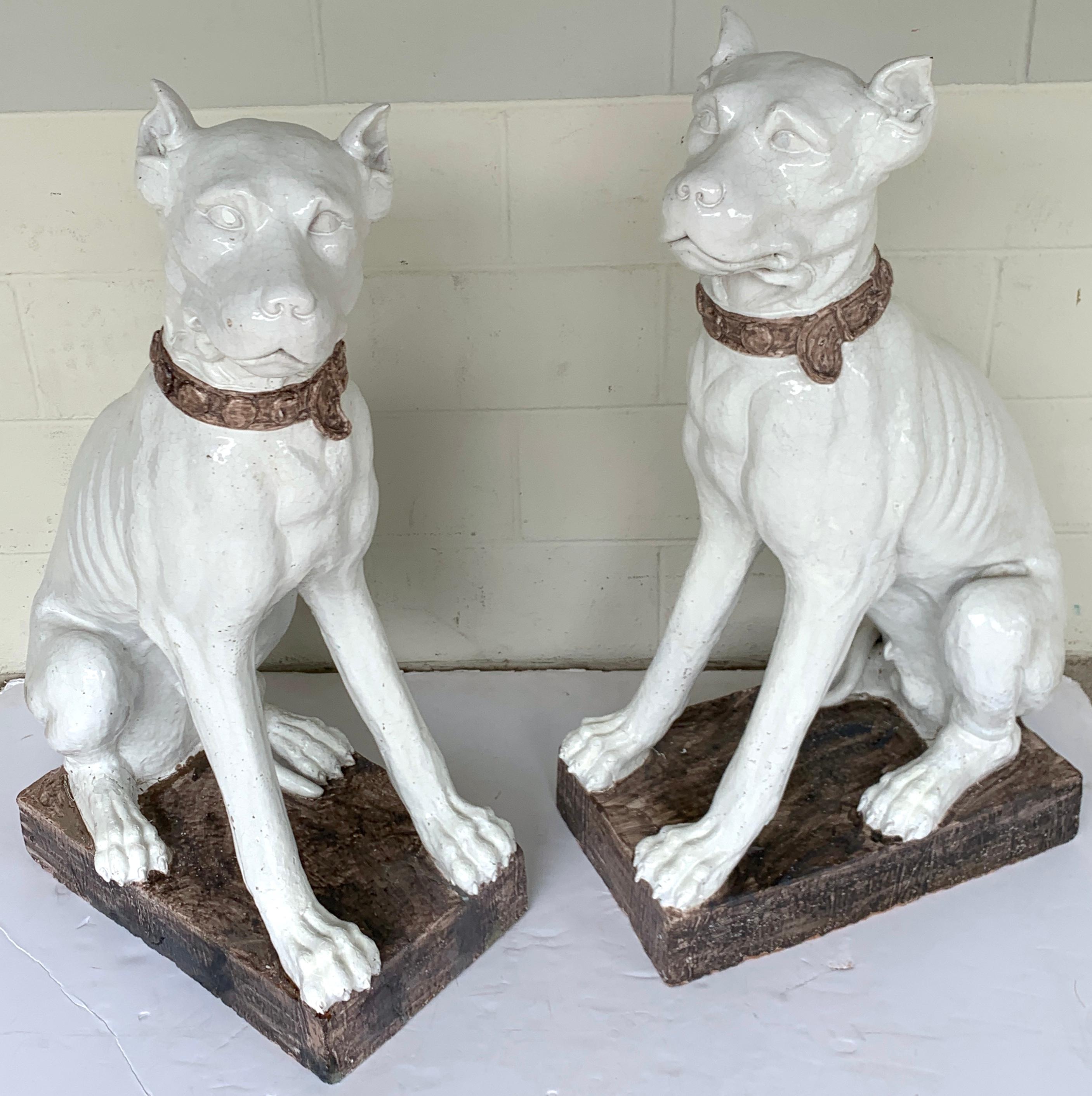 Monumental pair of Italian pottery figures seated white great Danes with collars, realistically modeled and painted, with expressive faces. One female, one male both seated on a rectangular 12.5