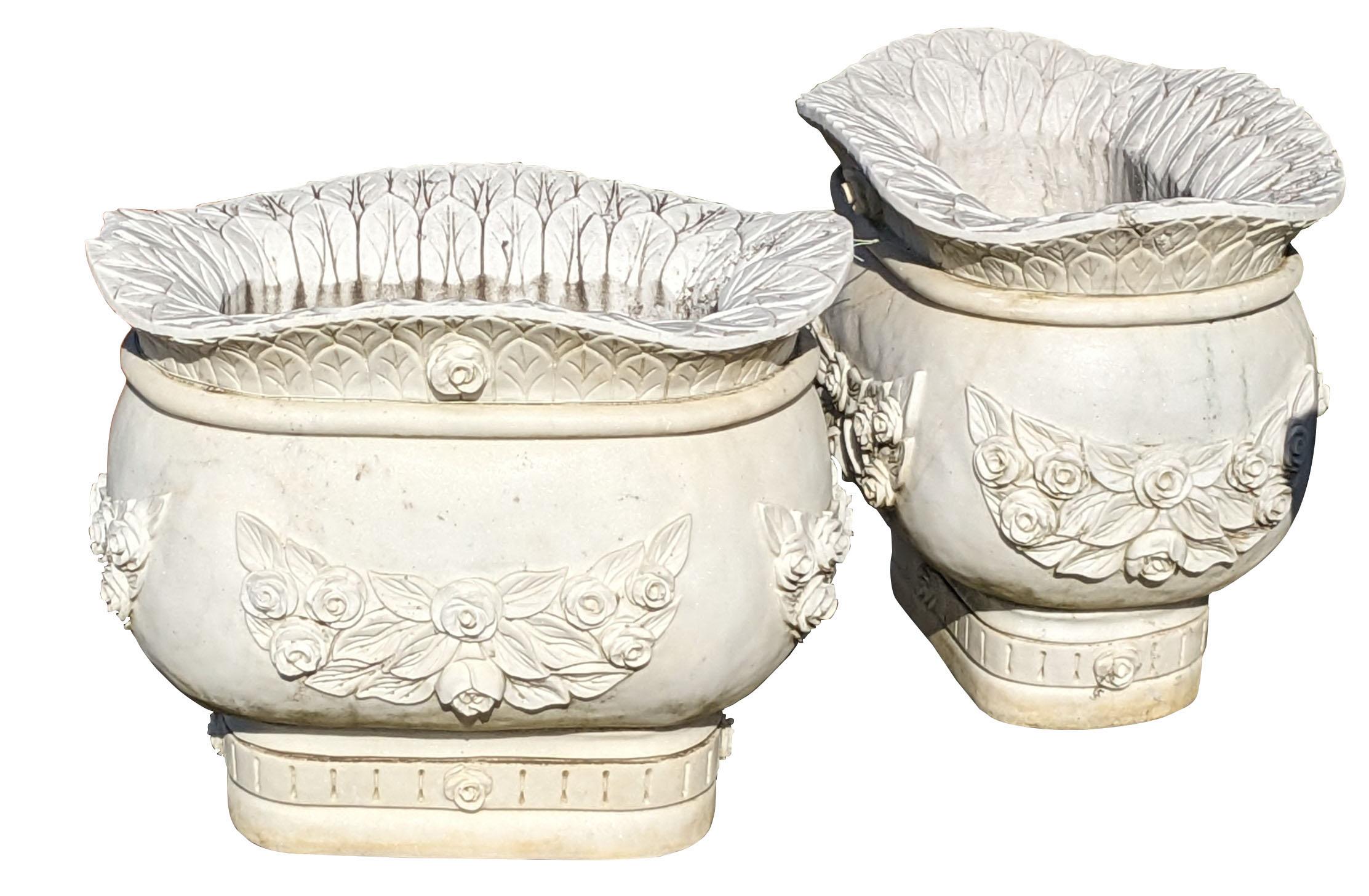 Una maestosa coppia di fioriere jardiniere in marmo italiano.  Ogni vaso massiccio è splendidamente decorato con un motivo di rose e foglie.  La ciotola o labbro è svasata in modo unico con una forma a dorso di cammello. Un bellissimo set che sarà