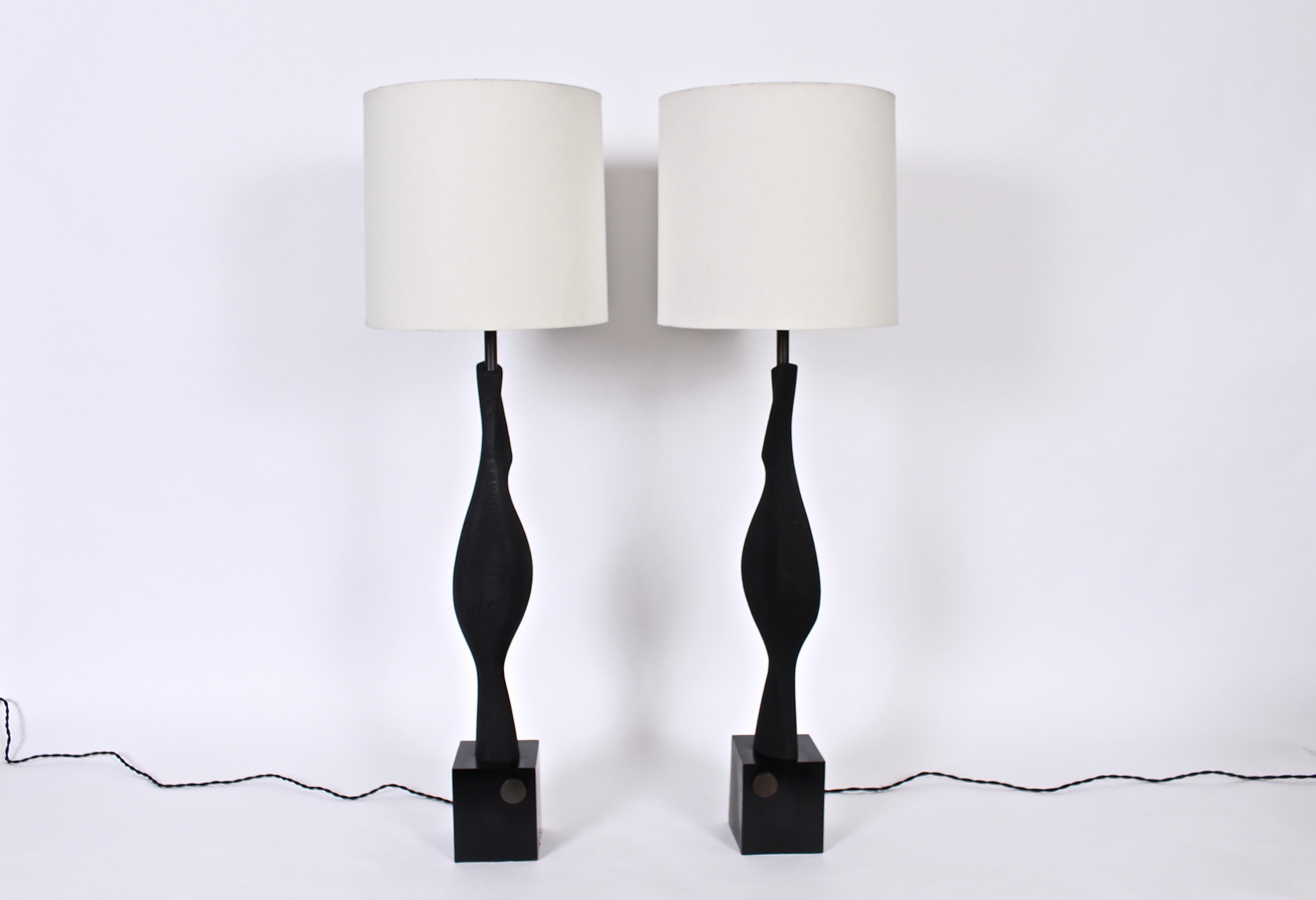 Statuesque pair of tall black grained wood Laurel Lamp Company table lamps, 1960s. Featuring a handcrafted, biomorphic black ebonized grained wood form on rectangular Black enameled metal platform base. With patinated brass disc light switch to