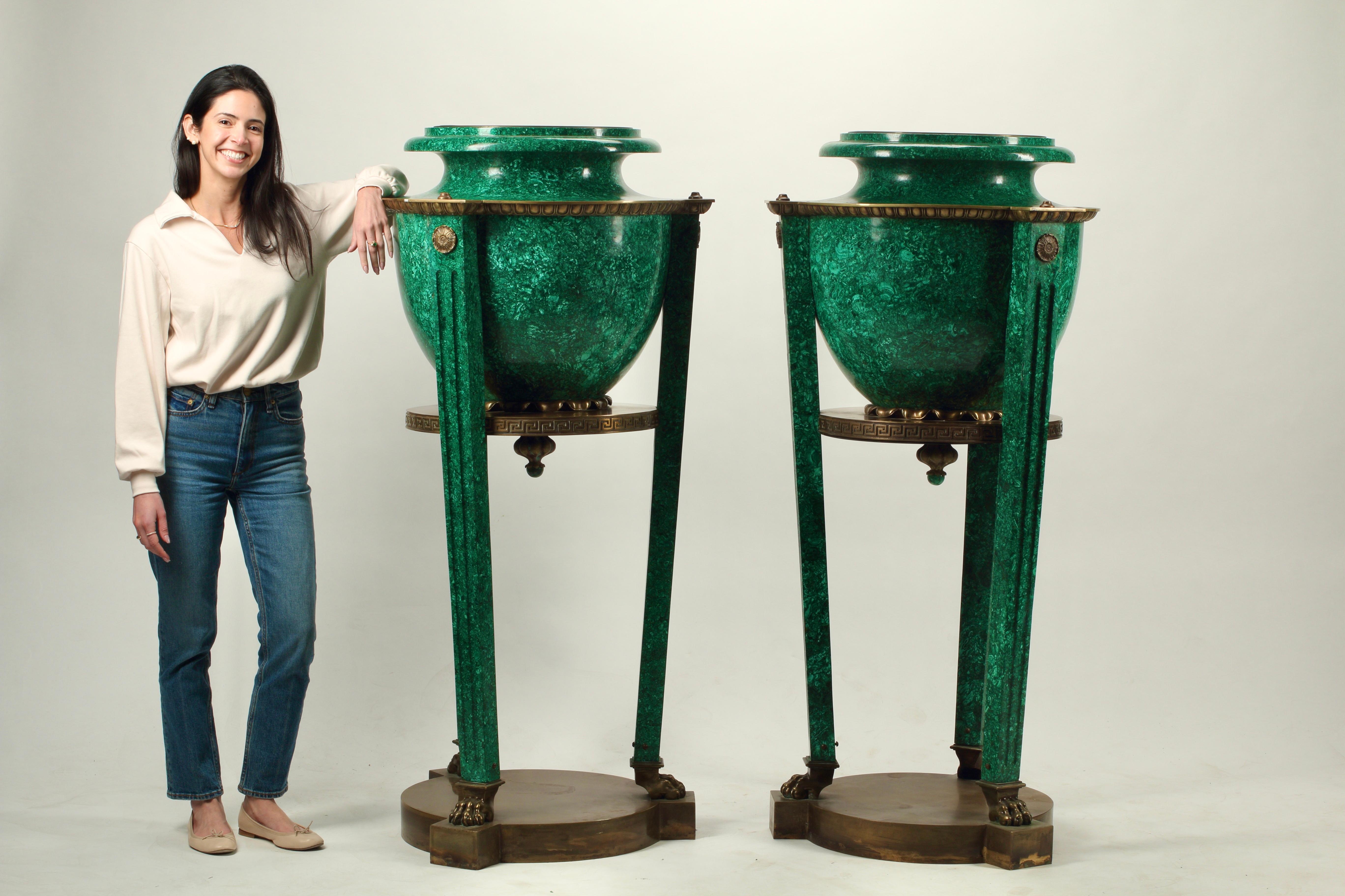 A magnificent large scale pair of neoclassical style carved malachite urns on stand with bronze mounts and and base. The urns sit handsomely on three fluted rectangular malachite legs fitted with bronze rosettes, claw feet and solid bronze base. The