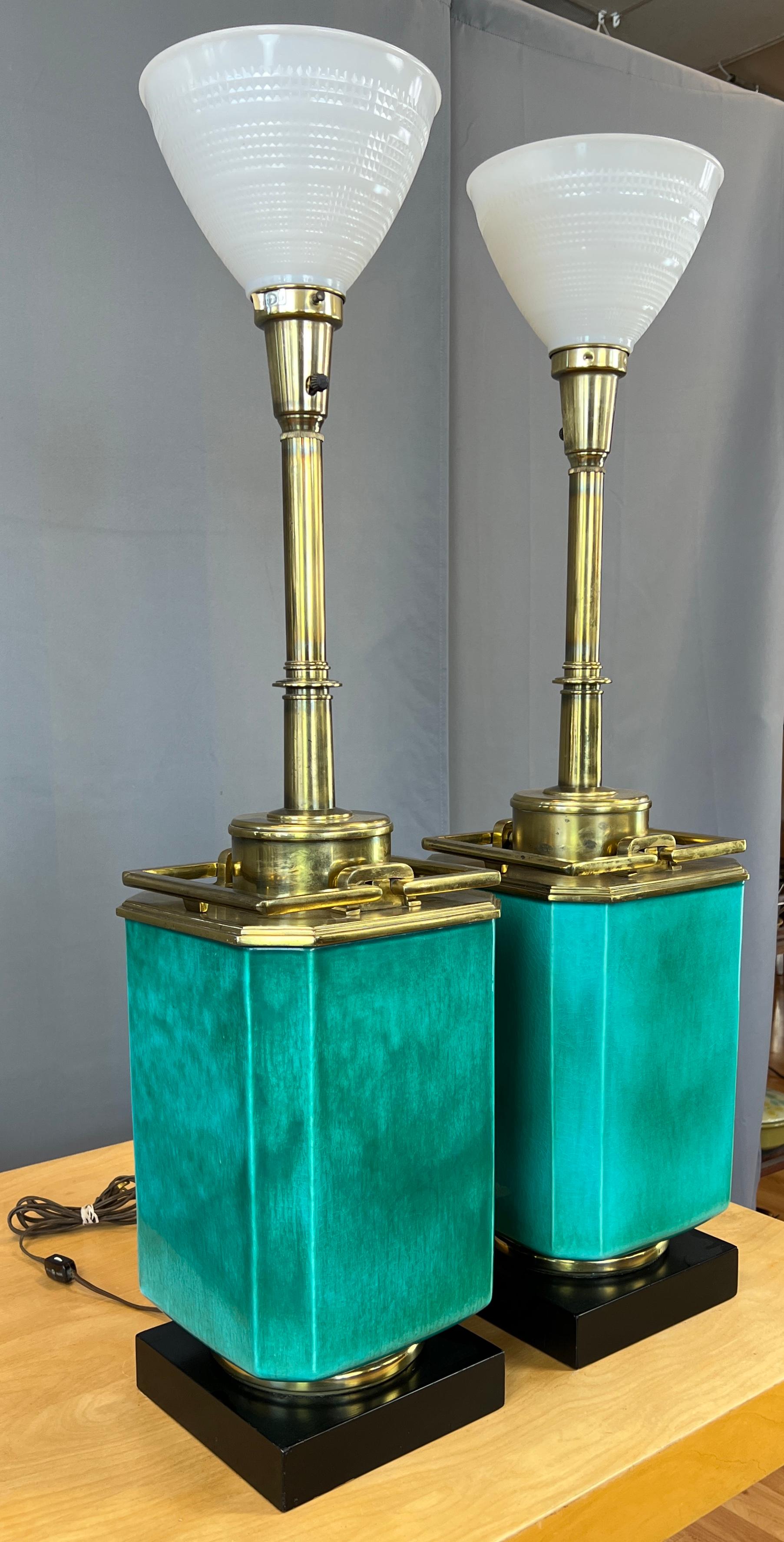 Une paire monumentale de lampes de table en turquoise et laiton par Edwin Cole pour Stiffel.
Il commence par un piédestal carré en bois noir surmonté d'un anneau en laiton, sur lequel se trouve le grand corps principal en céramique turquoise.
Au