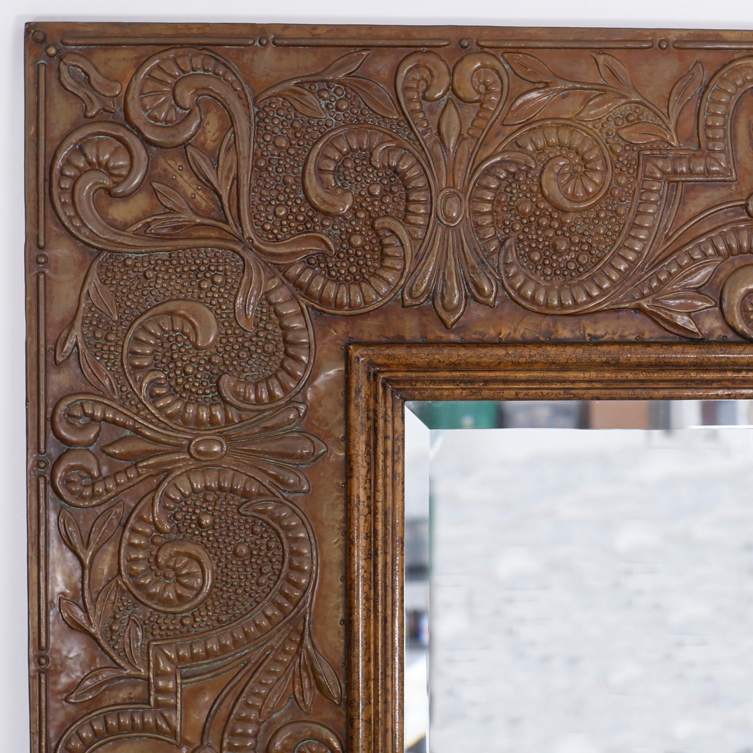 Large and impressive pair of beveled glass mirrors with a wood frame entirely clad in bronze with its original patina hand tooled with elaborate floral designs and a faux tortoise inner frame.