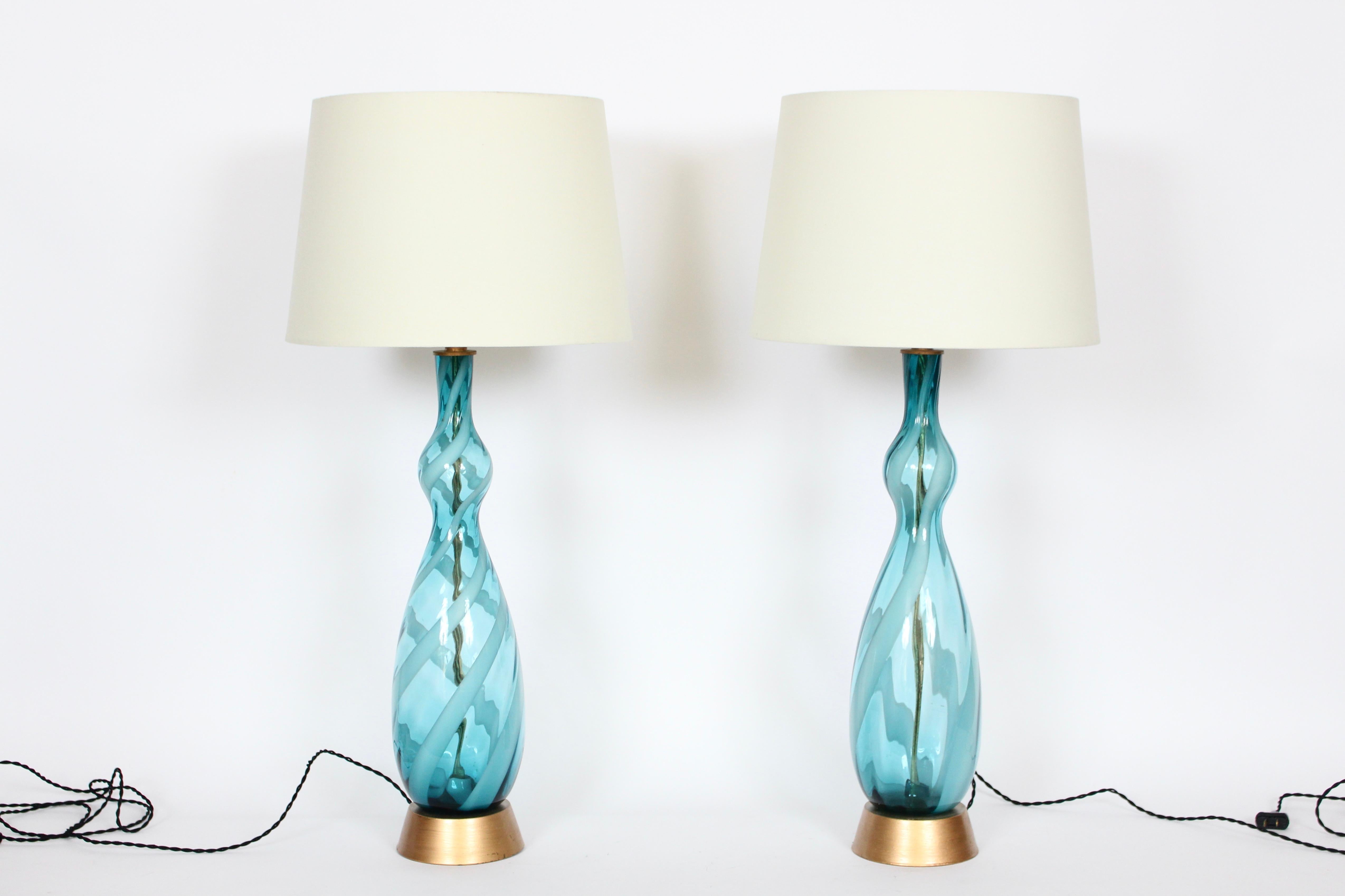 Tall pair of sea ocean blue and white frost swirl Murano glass table lamps. Featuring a tall hand blown, translucent bottle form, with pale white candy cane striping on splayed brass finished Metal bases. 27 H top of socket. Glass (with base) 23H.